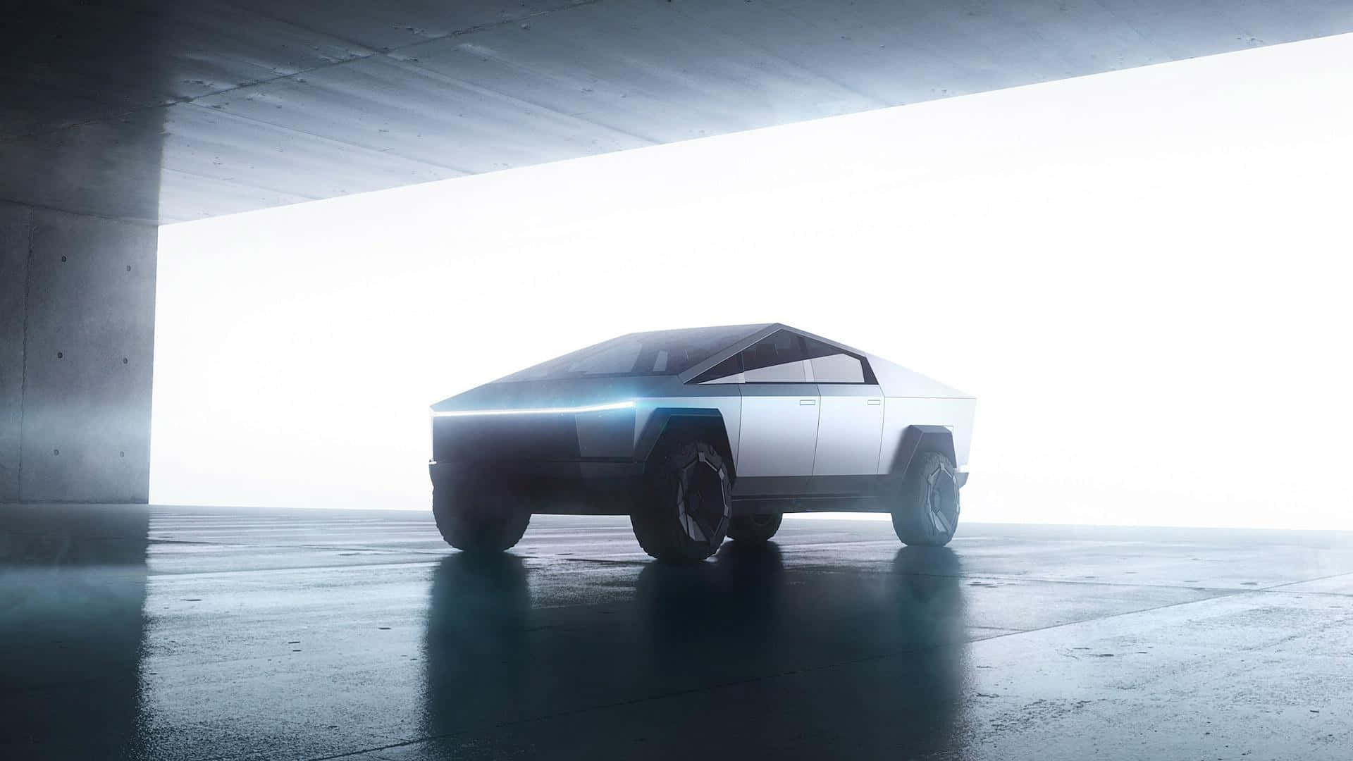 tesla 桌布 壁紙 — 一輛未來感十足的銀色 Tesla Cybertruck 在明亮的燈光下，於光禿禿的混凝土地下通道中閃閃發光，潮濕的路面反射著光線。