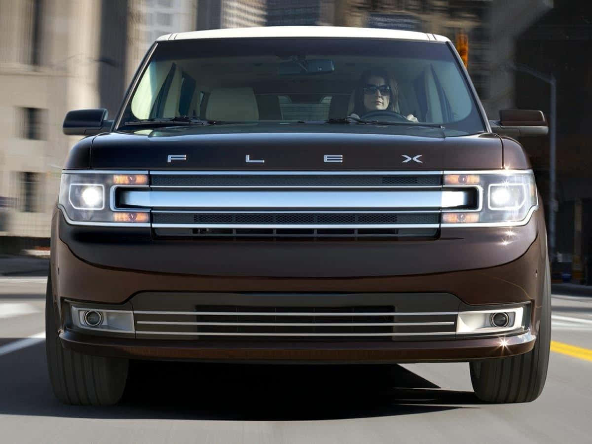 Ford Flex 桌布 壁紙 — 一輛棕色福特Flex SUV在城市的街道上向前行駛，一名戴太陽眼鏡的女子在駕駛。