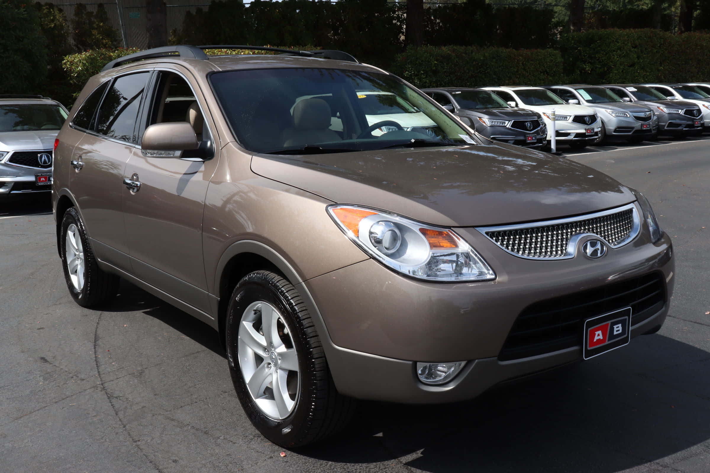 Hyundai Veracruz 桌布 壁紙 — 一輛棕褐色現代 Tucson SUV 停放在陽光明媚的停車場，背景有其他車輛。