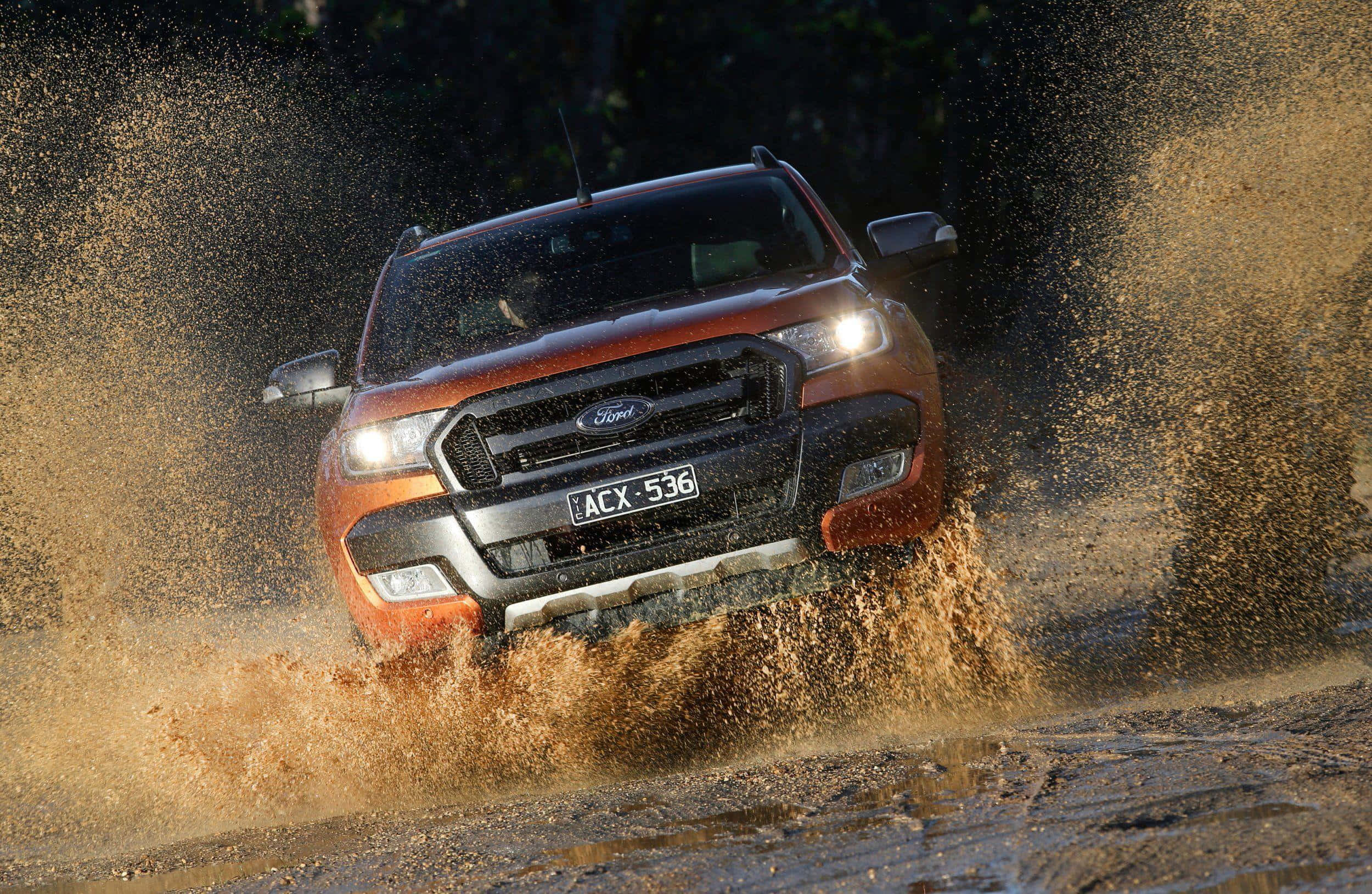 Ford Ranger 桌布 壁紙 — 一輛橙色的福特 Ranger 貨車強力駛過泥濘水坑，將棕色的水和泥土濺向四面八方。