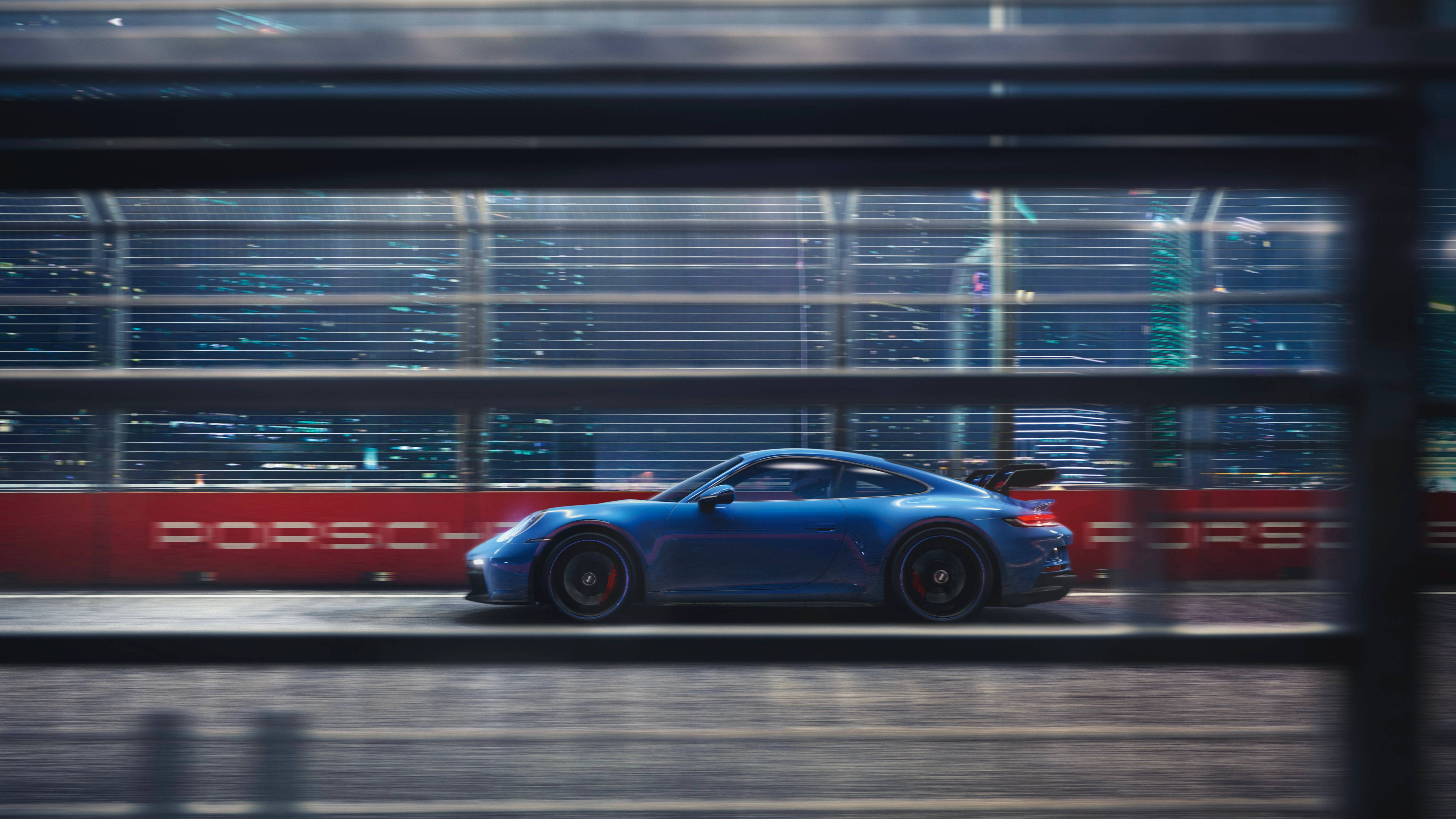 保時捷 桌布 壁紙 — 一輛流線型的藍色保時捷911 GT3在夜間穿過模糊的城市隧道，背後是閃爍的城市燈光。