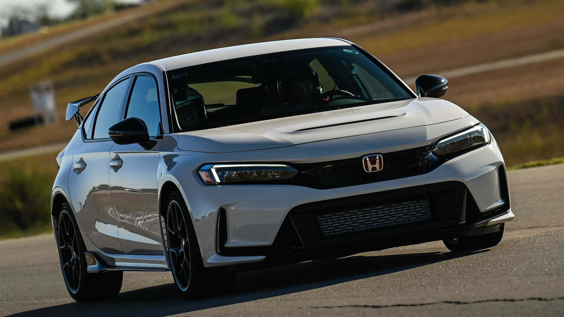 Honda Civic 桌布 壁紙 — 一輛流線型的銀色本田Civic Type R在陽光照耀的瀝青路上飛馳，背景是模糊的草坡。