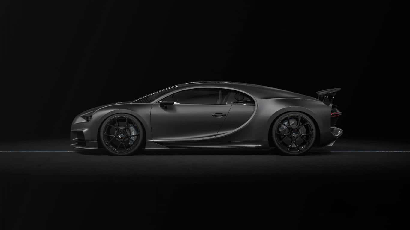 啞光黑色 桌布 壁紙 — 一輛流線型磨砂灰色Bugatti Chiron跑車在強烈的黑色工作室背景下，以戲劇性的聚光燈側面滑行。