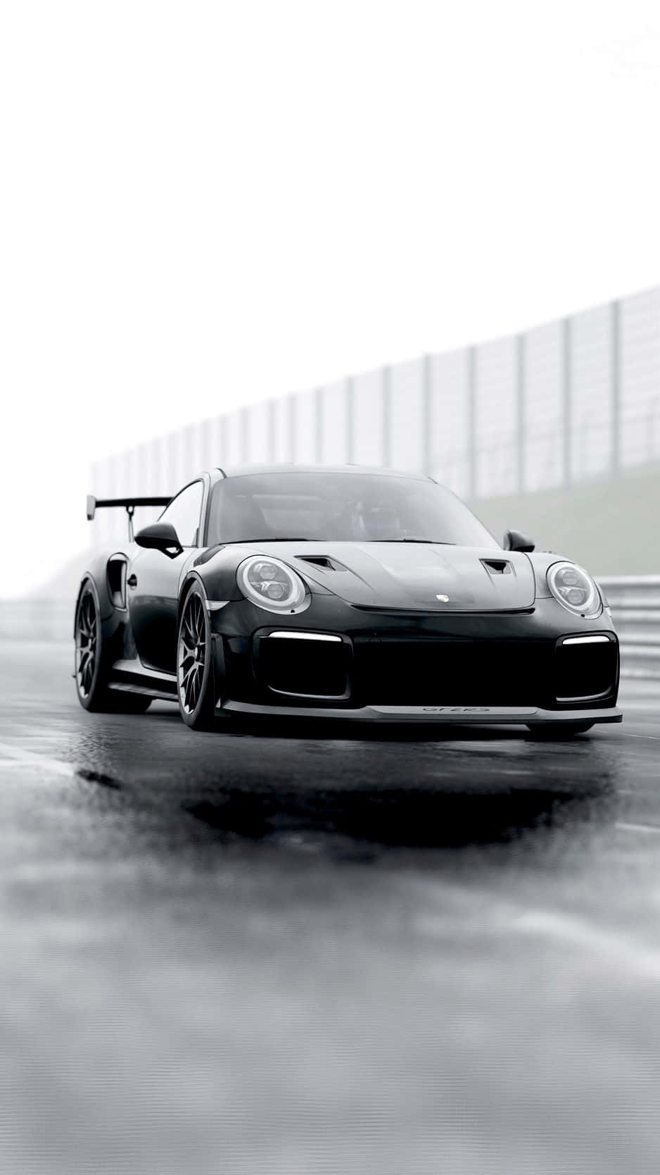 Porsche iPhone 桌布 壁紙 — 一輛流線型黑色保時捷911 GT2 RS在潮濕的賽道上奔馳，天空多雲，帶有動態模糊效果。