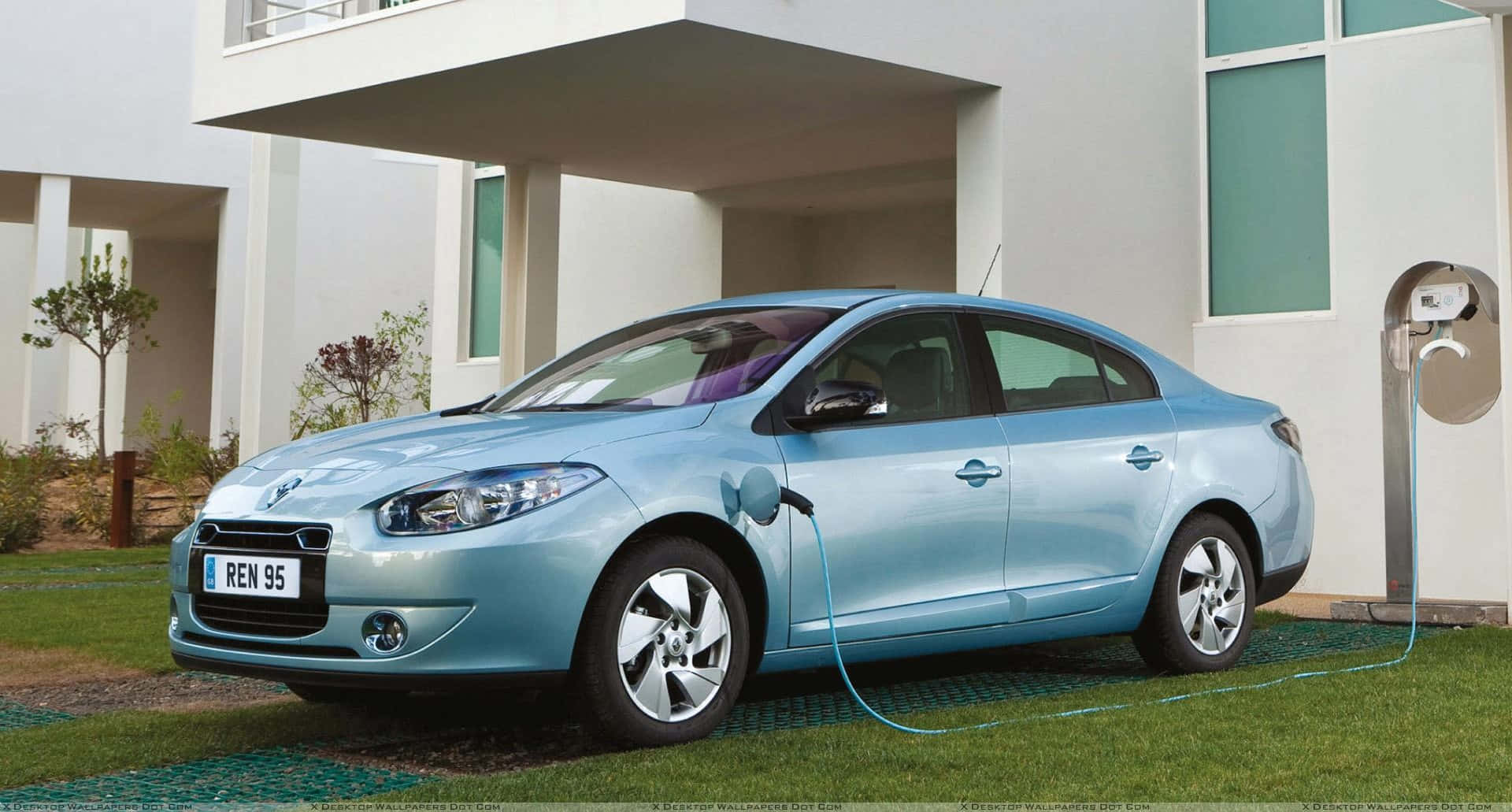 Renault Fluence 桌布 壁紙 — 一輛淺藍色電動車在現代白色房屋旁的草地上充電，房屋設有充電站。