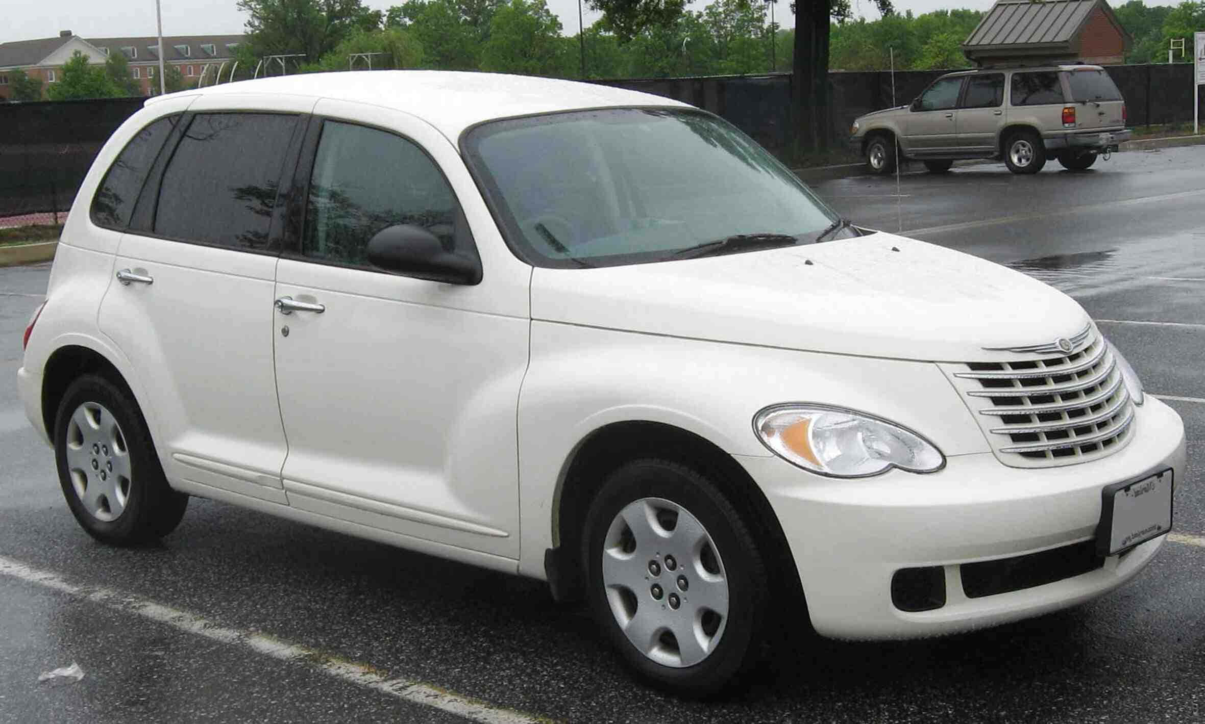 Chrysler Pt Cruiser 桌布 壁紙 — 一輛白色 Chrysler PT Cruiser 停泊在濕漉漉的瀝青停車場，背景有樹木和圍欄。