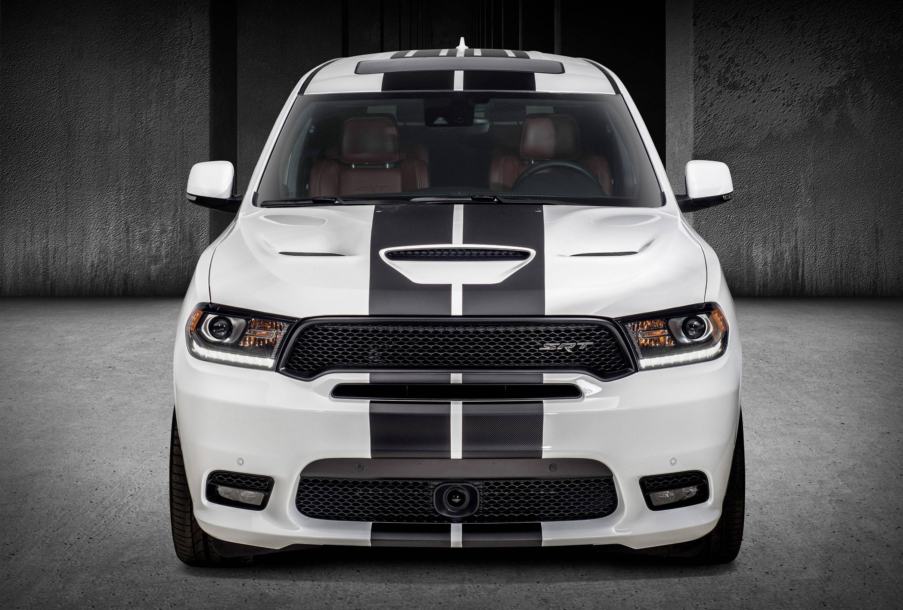 Mopar 2019 Dodge Durango SRT 壁紙 — 一輛白色 Dodge Ram SRT 帶有醒目黑色賽車條紋，停泊在簡樸的混凝土車庫中，散發出原始力量和侵略性設計。