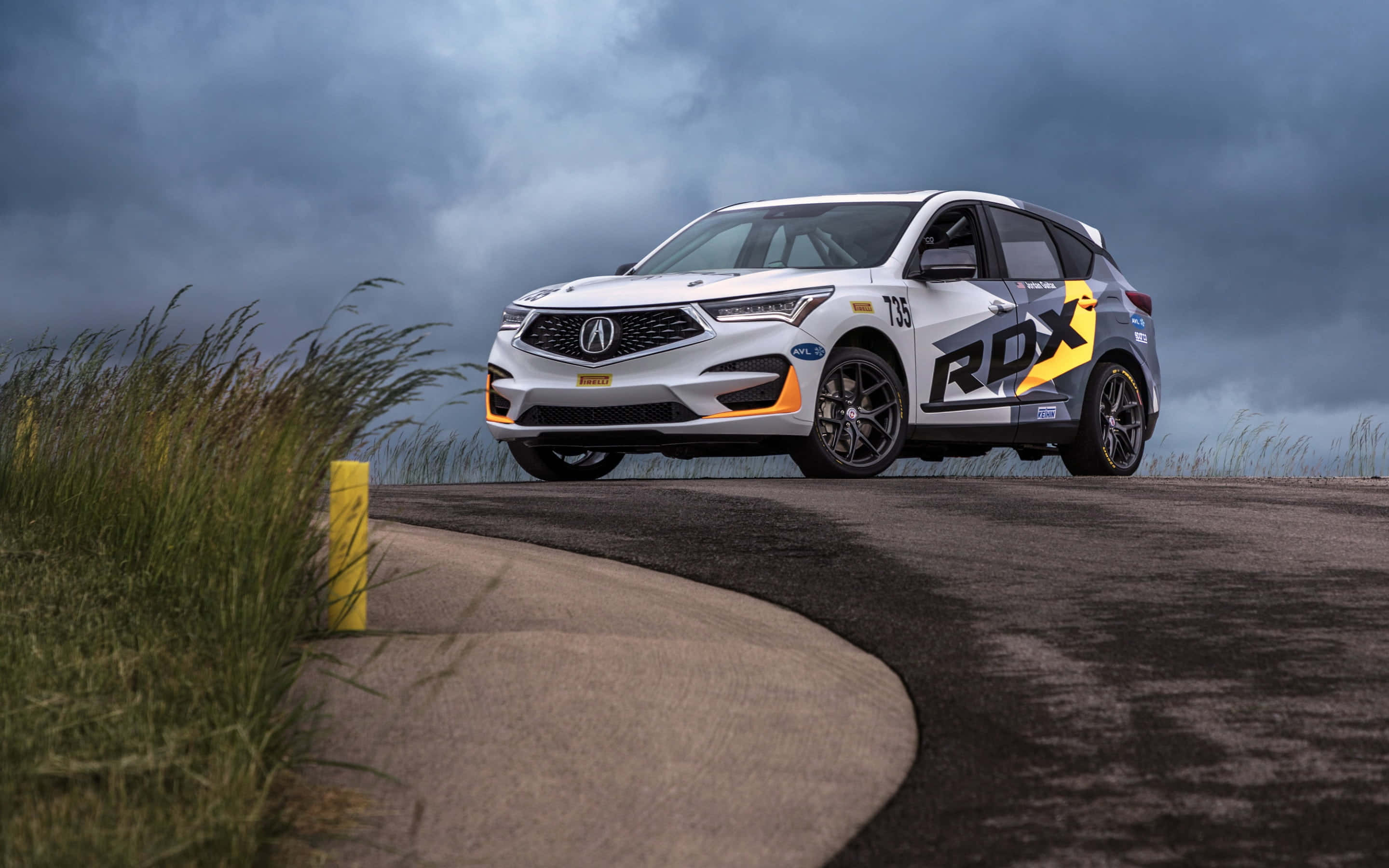 Acura Rdx 桌布 壁紙 — 一輛白色Acura RDX賽車，帶有醒目的黃色和黑色貼花，在戲劇性的暴風雨天空下行駛在蜿蜒的瀝青路上。