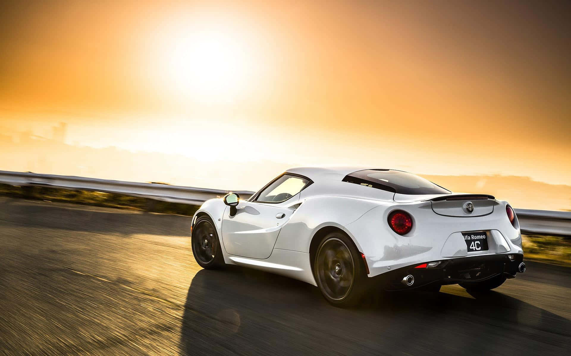 Alfa Romeo 4c 桌布 壁紙 — 一輛白色Alfa Romeo 4C跑車在日落時分沿著海岸公路飛馳，金色光芒劃過路面。