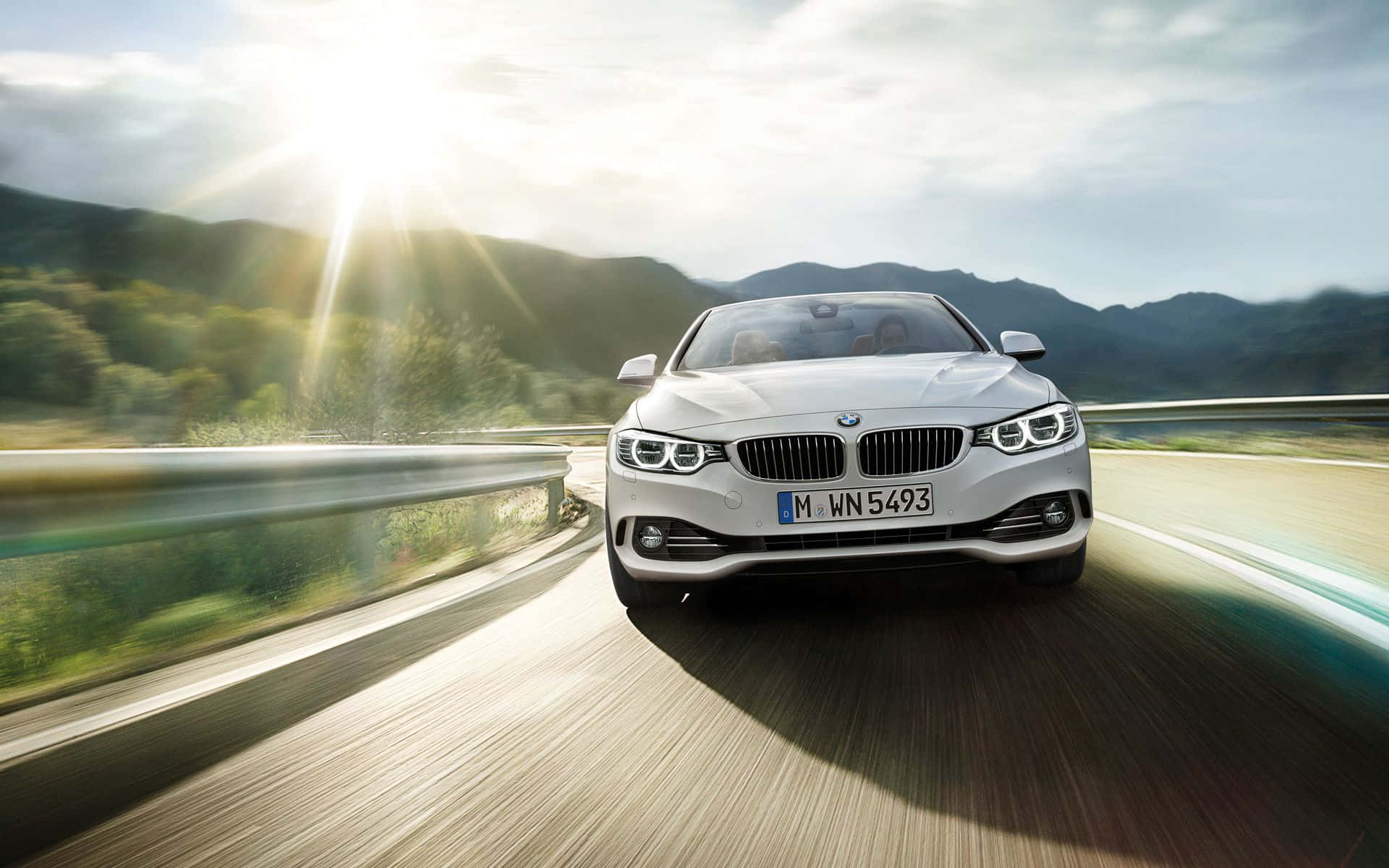 Bmw 4 Series 桌布 壁紙 — 一輛白色BMW開篷跑車在蜿蜒的山路上疾馳，伴隨著陽光爆發的照明和模糊的動態效果。