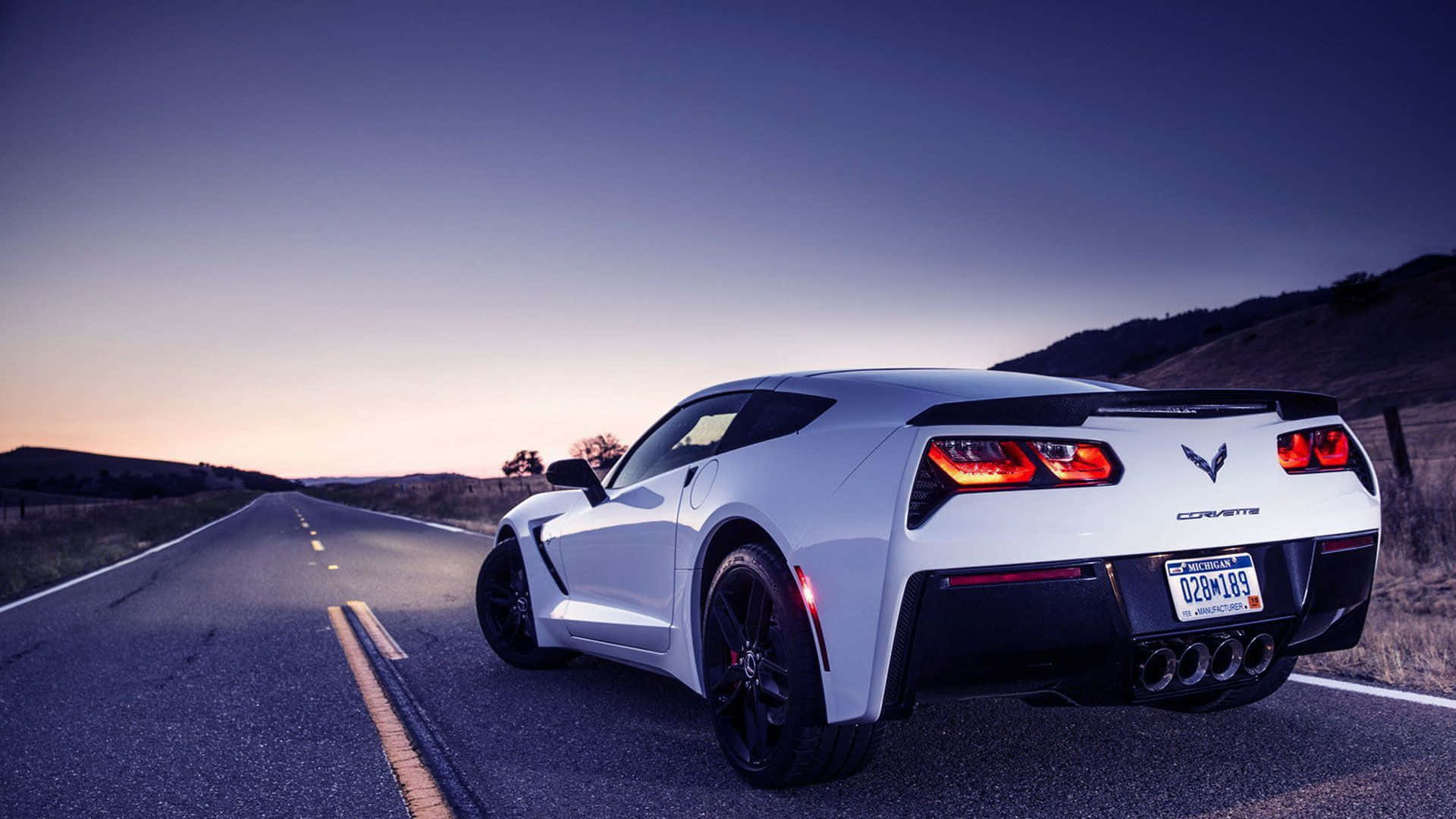Chevrolet Corvette Z06 桌布 壁紙 — 一輛白色Corvette跑車在暮色中沿沙漠公路行駛，紅色尾燈閃爍發光。
