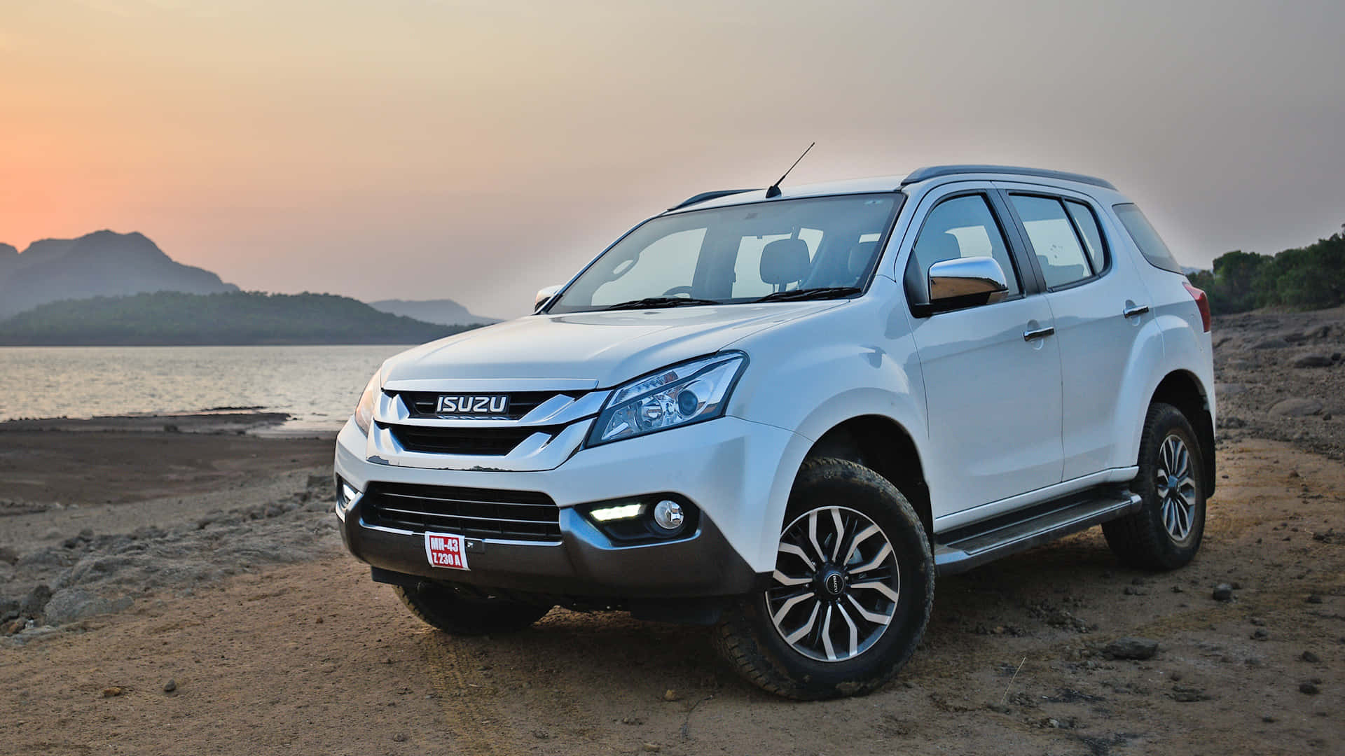 Isuzu 桌布 壁紙 — 一輛白色Isuzu pickup truck在日落時停泊在泥土岸邊，背景有山和水。