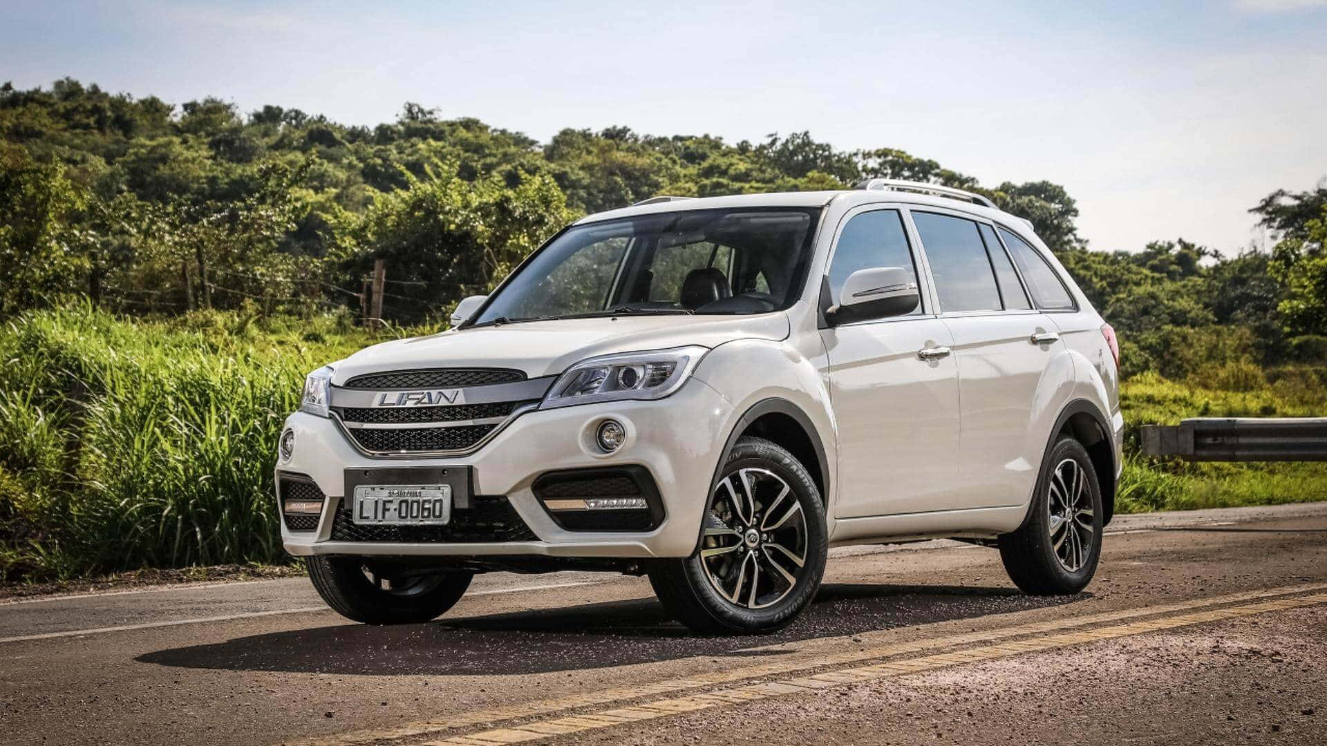 Lifan 桌布 壁紙 — 一輛白色Lifan SUV在陽光明媚的鄉村道路上行駛，兩旁是茂密的綠色樹葉和高高的草叢，頭頂是清澈的藍天。