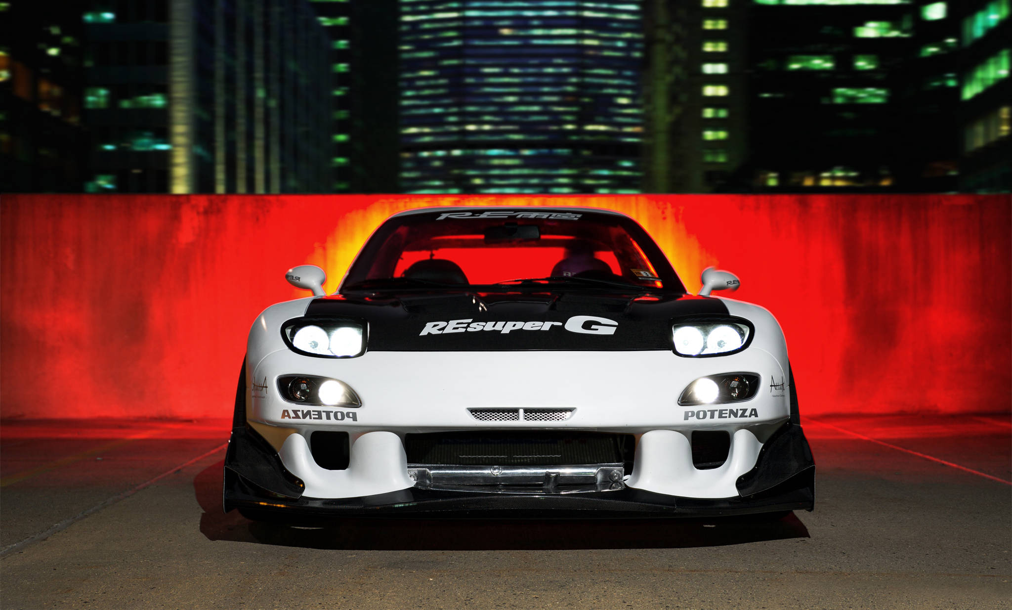 Mazda 桌布 壁紙 — 一輛白色Mazda RX-7 FD3S帶有REsuper G塗裝，正面朝向發光的紅色牆壁，背後是霓虹燈照亮的摩天大樓。