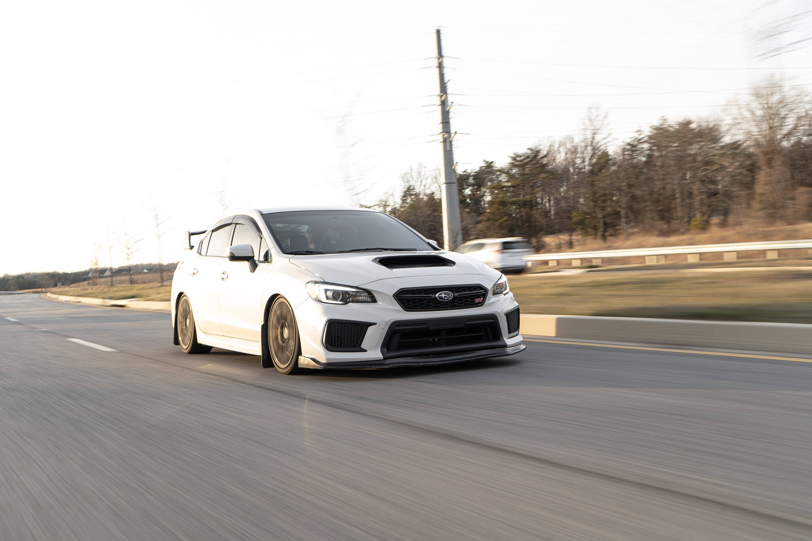 subaru 桌布 壁紙 — 一輛白色Subaru WRX STI在鄉村高速公路上高速行駛，動態模糊傳達出高速度和力量。