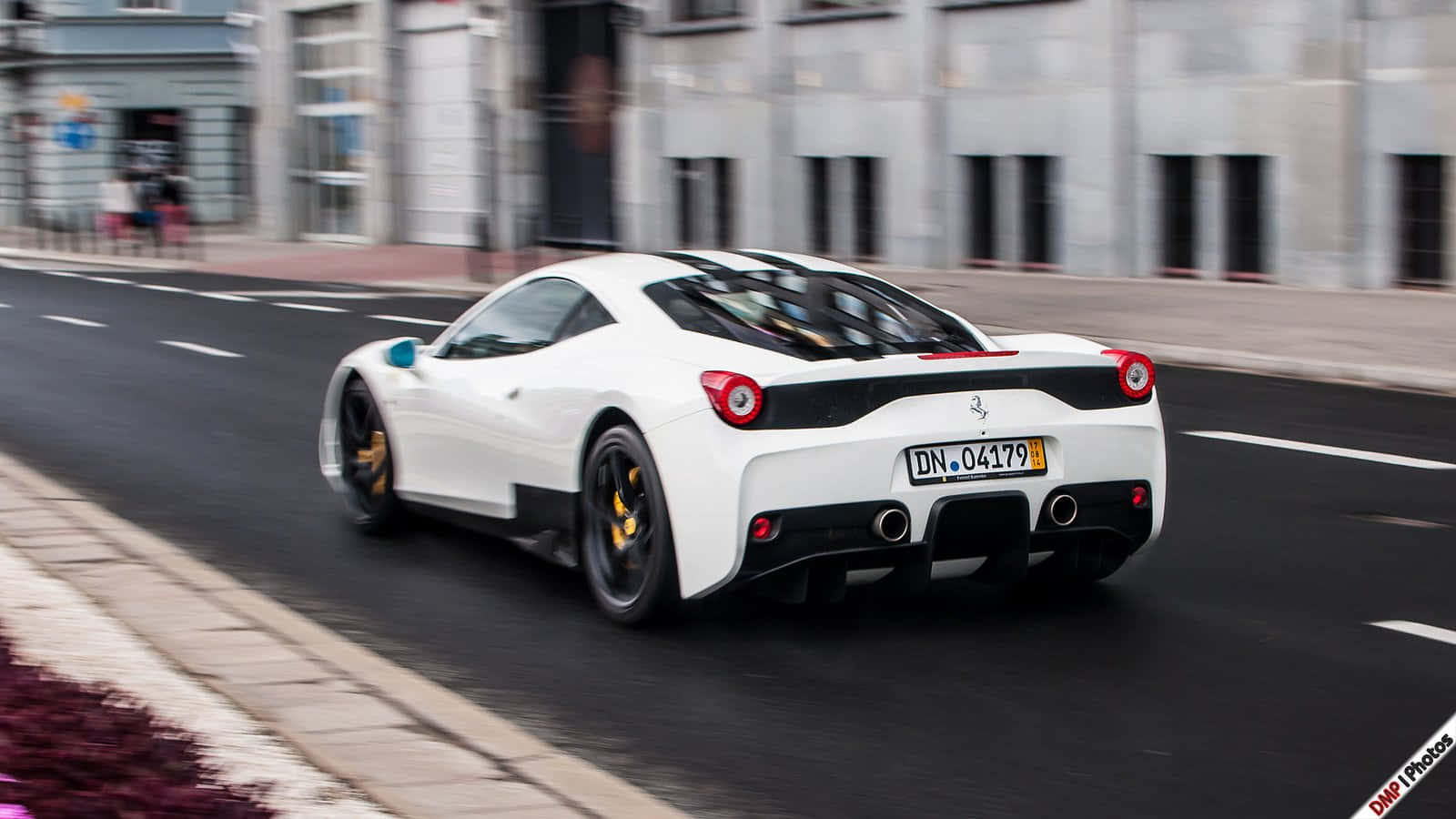 Ferrari 458 Speciale 桌布 壁紙 — 一輛白色法拉利跑車配備黃色制動卡鉗，在模糊建築物背景的城市街道上飛馳。