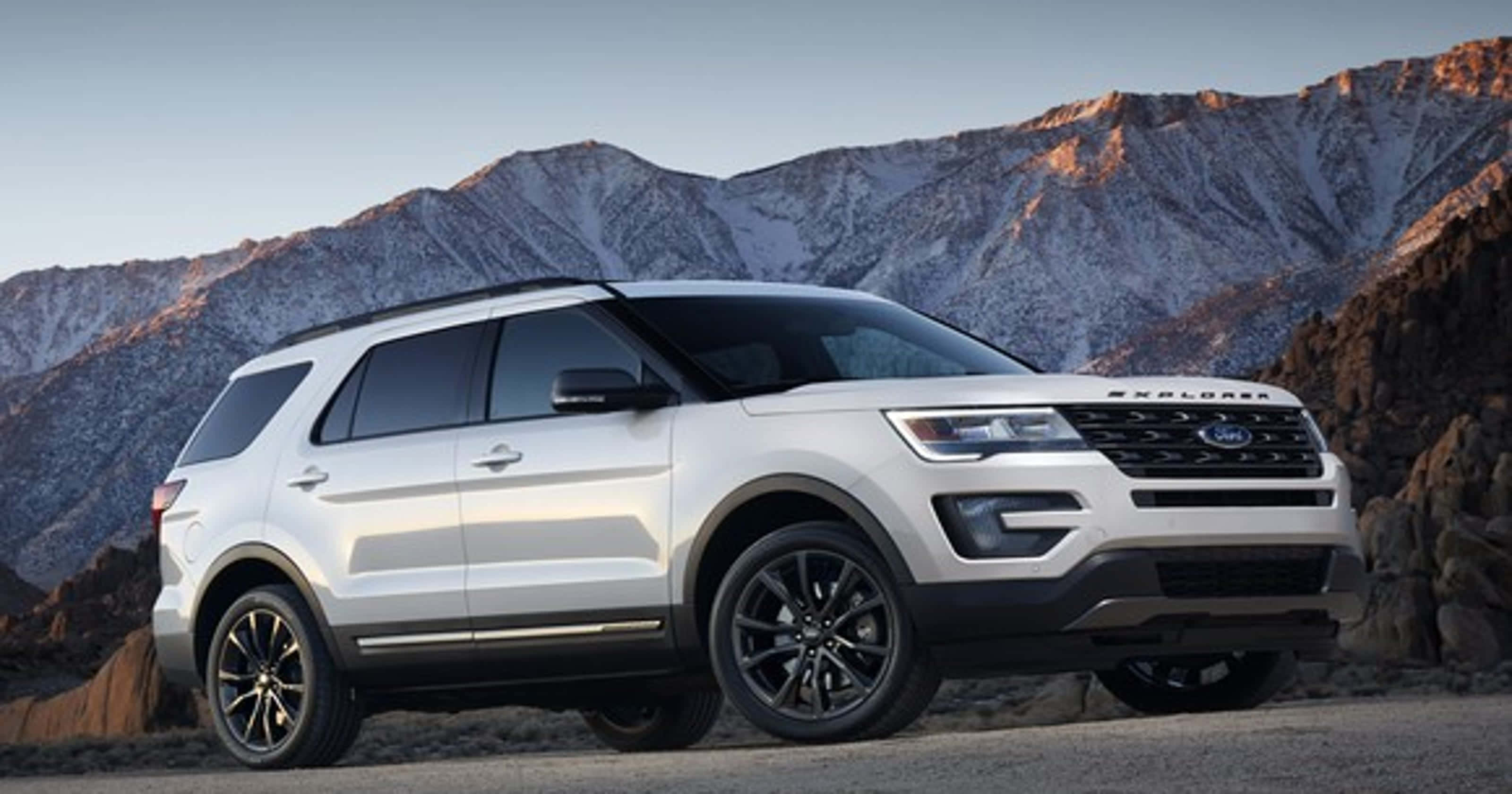 Ford Explorer 桌布 壁紙 — 一輛白色福特Explorer SUV停在沙漠公路上，背景是日落時分積雪覆蓋的山脈。