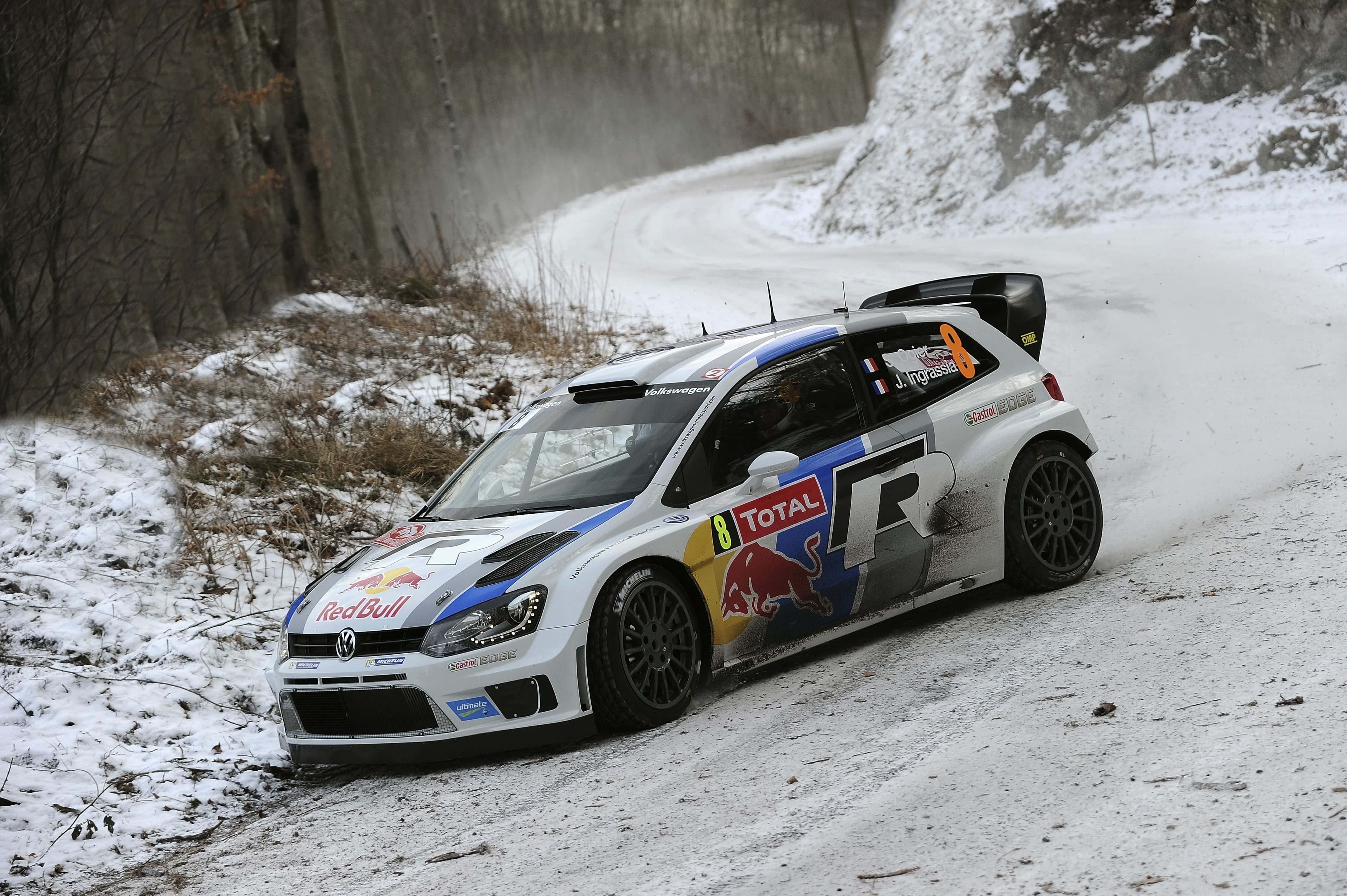 Ice Racing 桌布 壁紙 — 一輛白色紅牛拉力賽車在積雪的森林彎路上飛馳，激起雪霧。