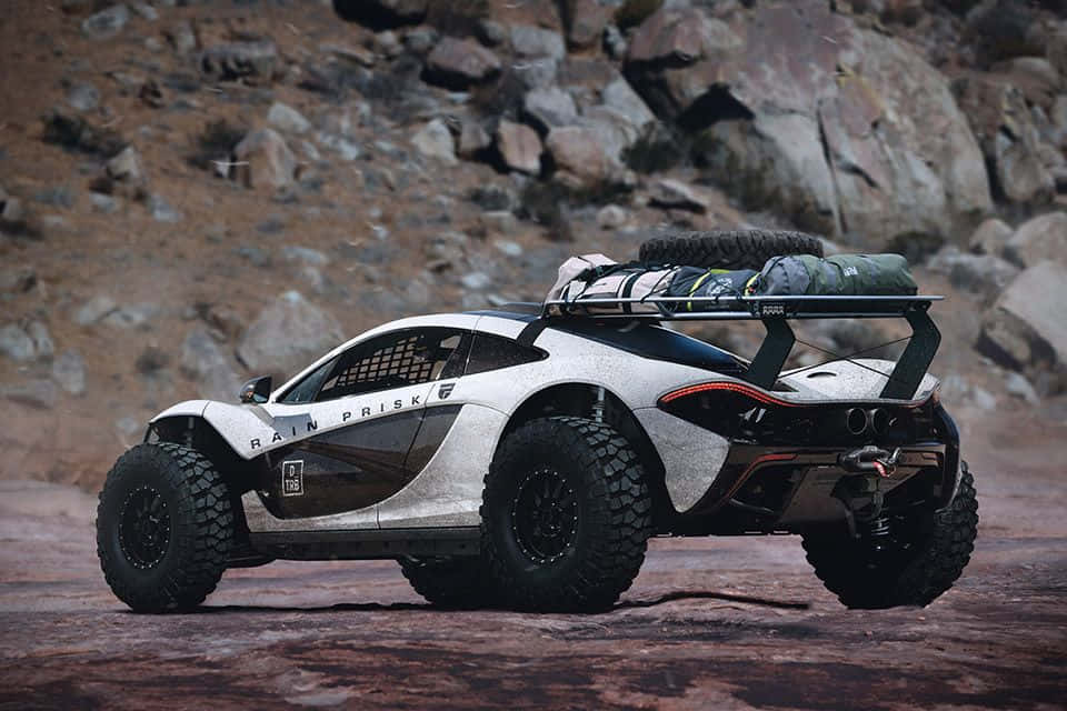 Off-road Car 桌布 壁紙 — 一輛白色越野McLaren跑車，配備超大輪胎和車頂行李裝備，停泊在岩石地形上。