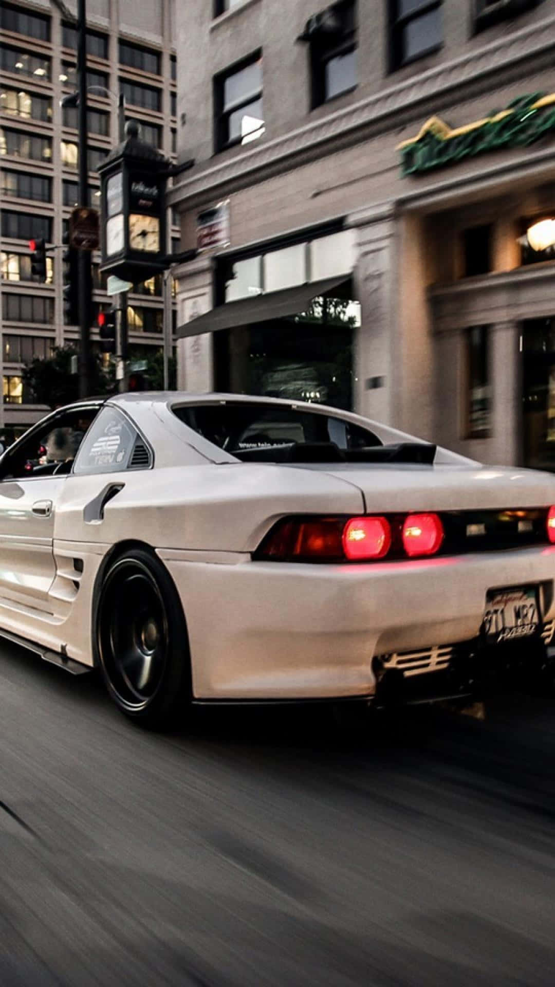 Tuned Car 桌布 壁紙 — 一輛白色跑車在黃昏時分高速駛過城市街道，帶有模糊的動態效果和發光的紅色尾燈。