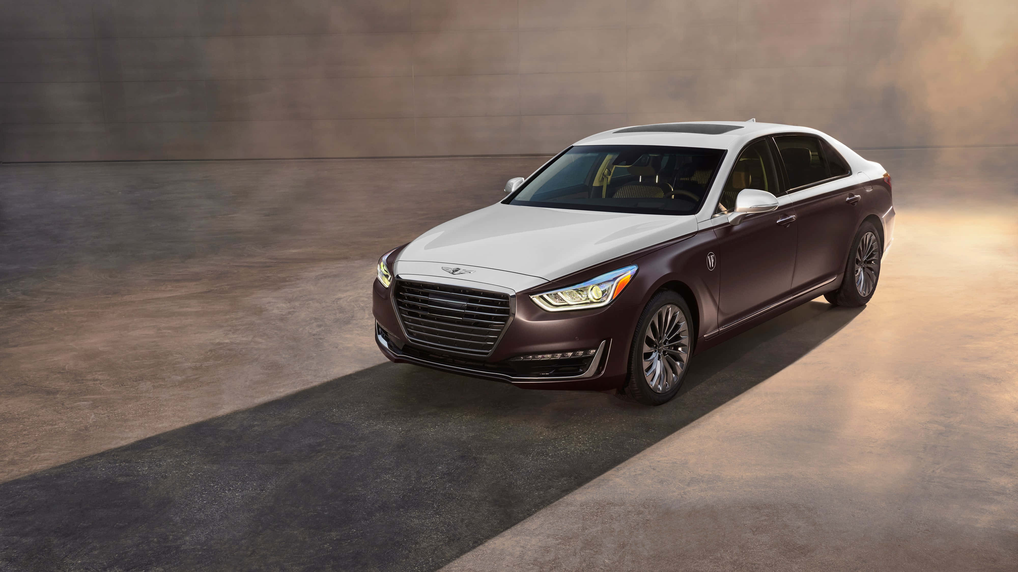 Genesis G90 桌布 壁紙 — 一輛白色車頂、栗色車身的豪華雙色調轎車，在簡約混凝土地板上，於溫暖的攝影棚燈光下閃閃發光。