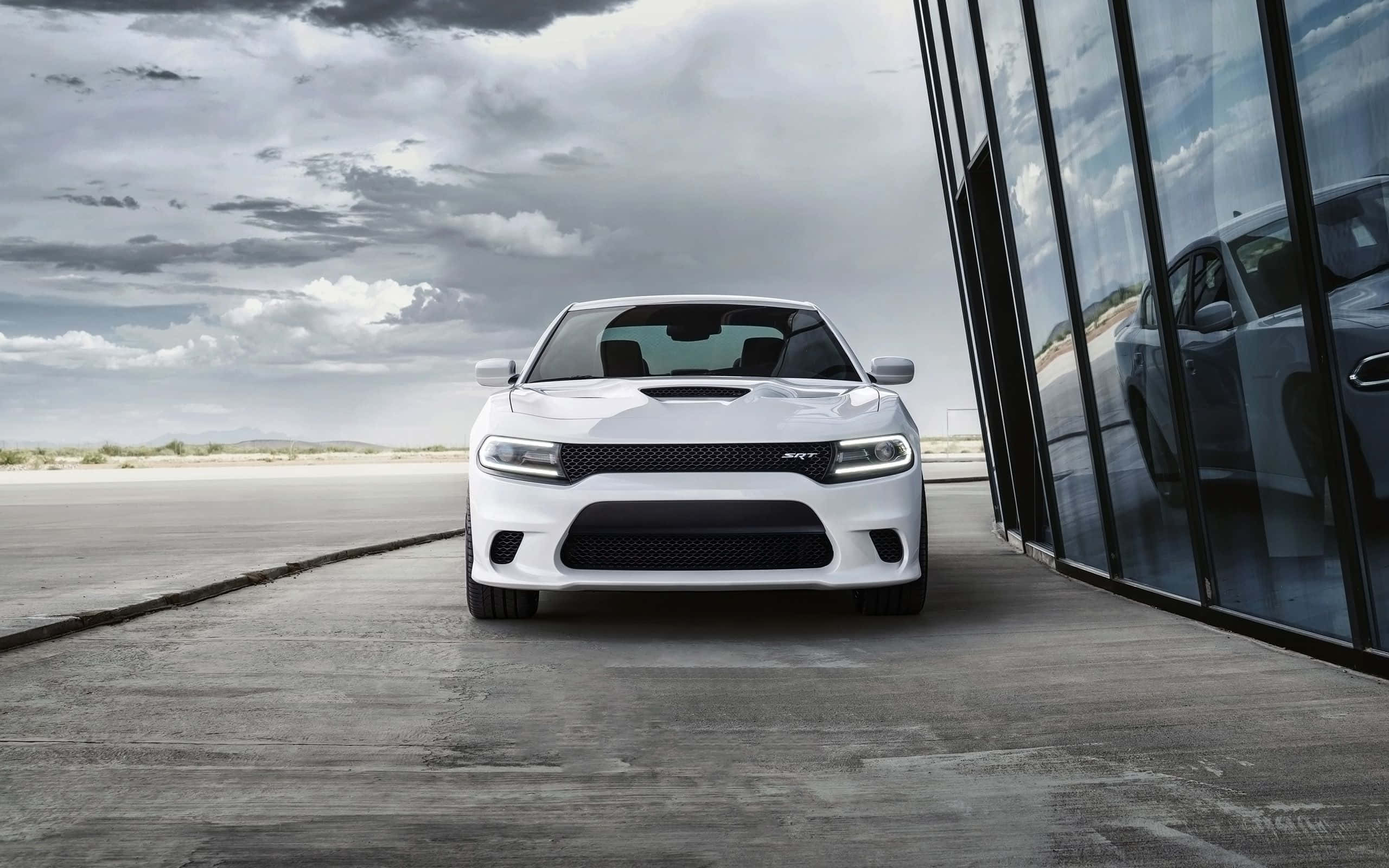 Dodge Charger 桌布 壁紙 — 一輛白色道奇挑戰者SRT Hellcat停泊在玻璃建築旁邊的混凝土上，天空多雲。
