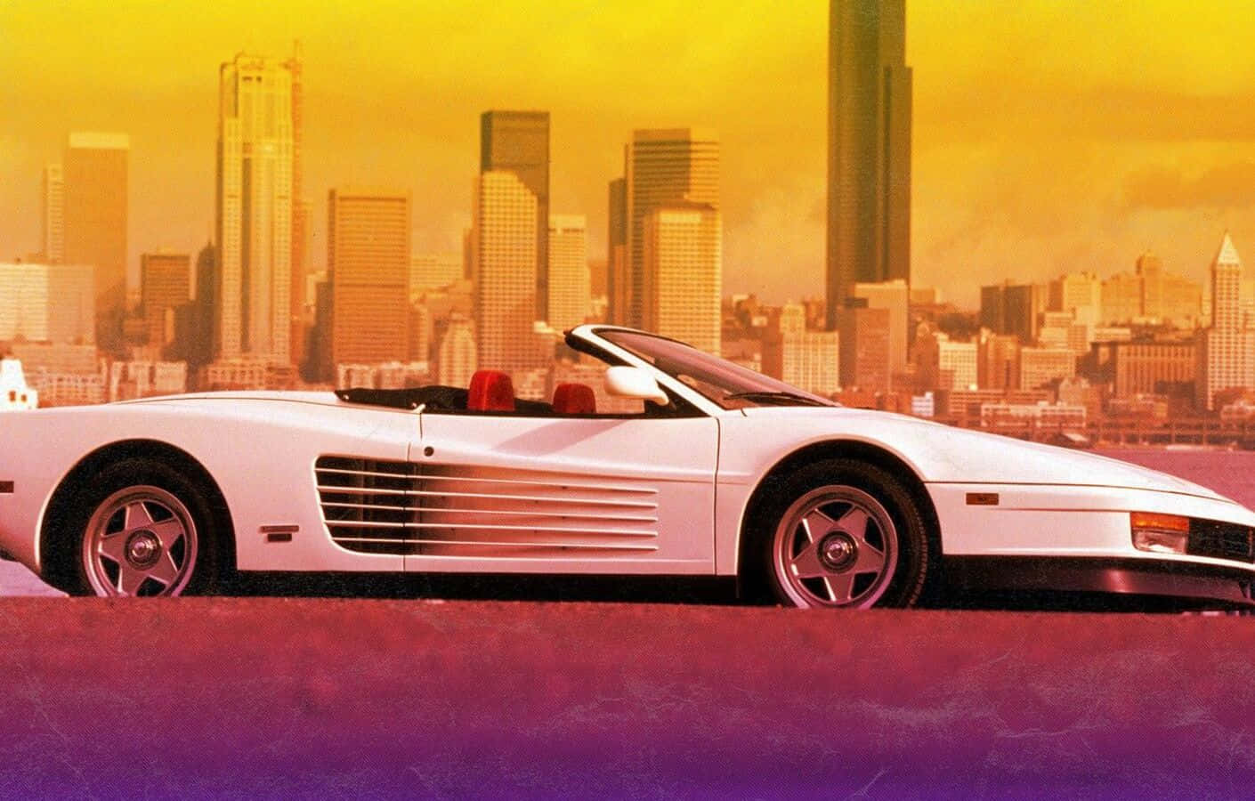 Ferrari Testarossa 桌布 壁紙 — 一輛白色開篷跑車配紅色座椅，停放在紫色表面上，背景是日落時分金黃色的城市天際線。