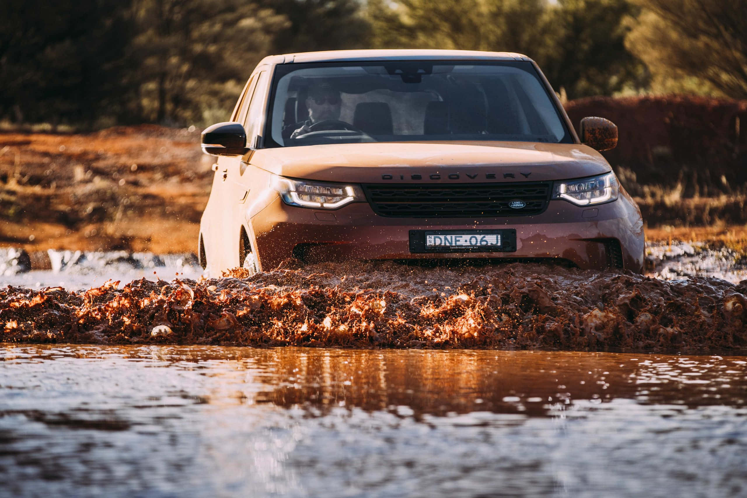 Land Rover Discovery 桌布 壁紙 — 一輛米色Land Rover Discovery駛過厚厚的棕色泥坑，泥水在車輪周圍飛濺。