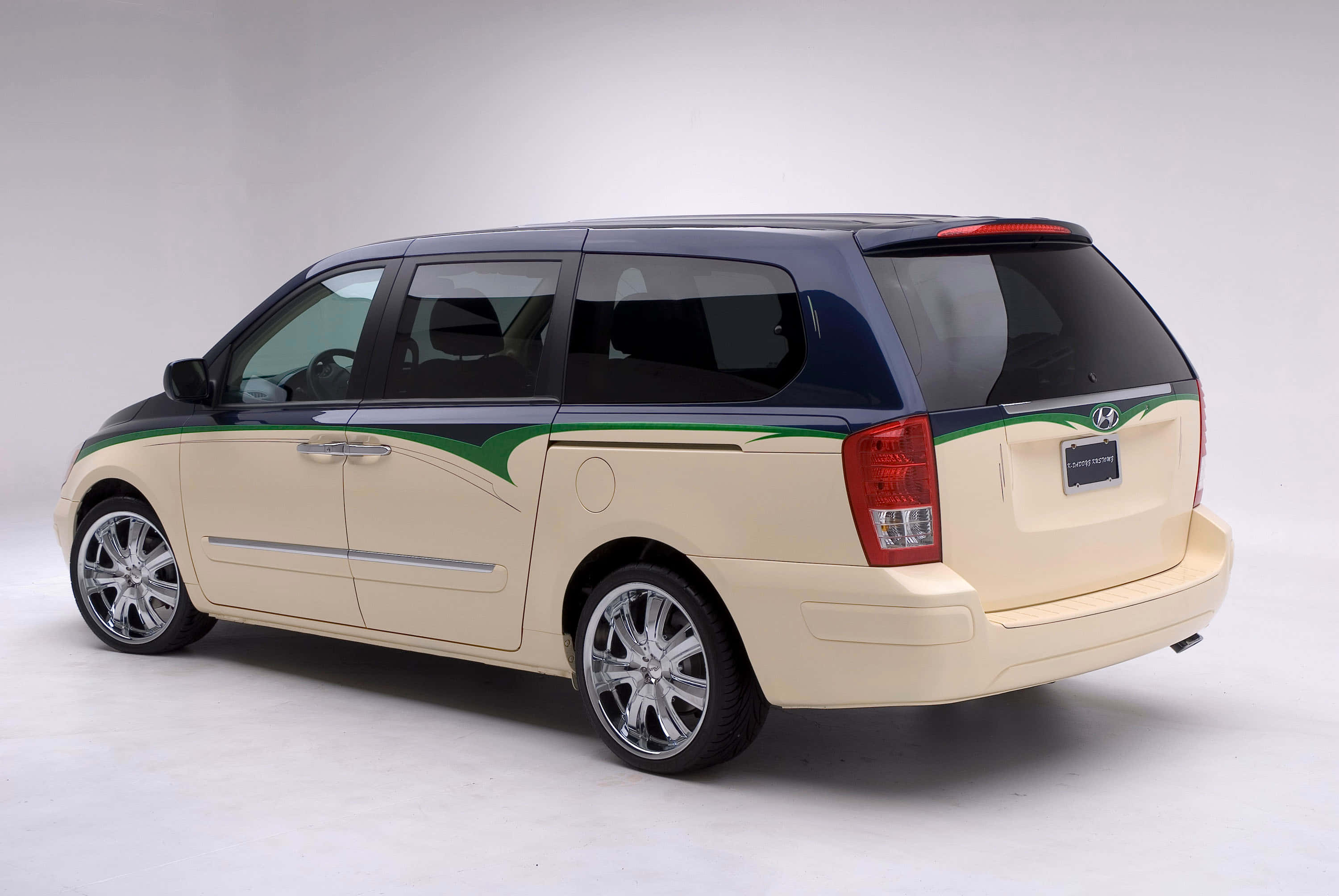 Hyundai Entourage 桌布 壁紙 — 一輛米色和黑色的現代迷你廂型車，帶有綠色飾條和鍍鉻輪圈，在攝影棚內拍攝。