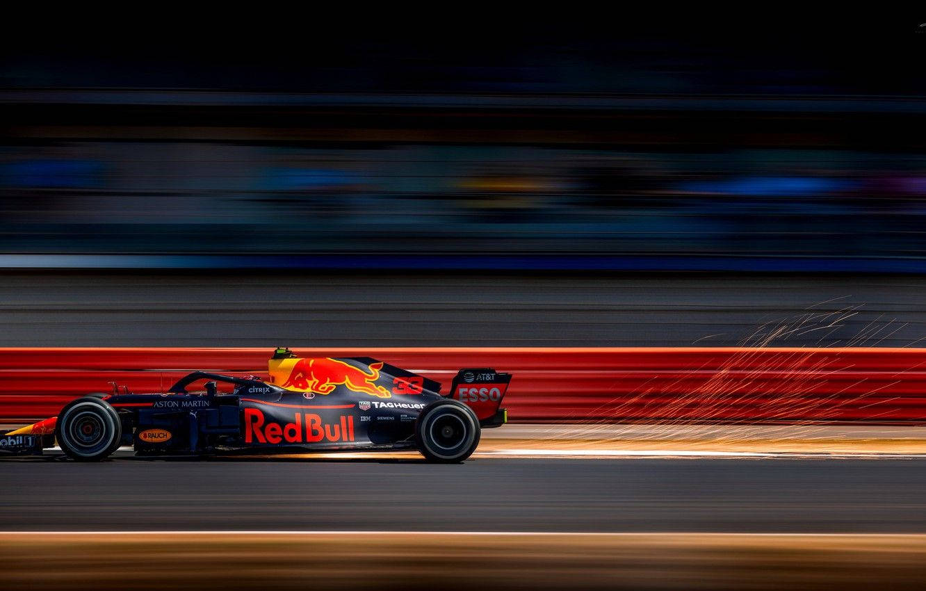 Verstappen 桌布 壁紙 — 一輛紅牛F1賽車在夜間賽道上高速駛過，帶有動態模糊效果，輪胎飛濺出火花。