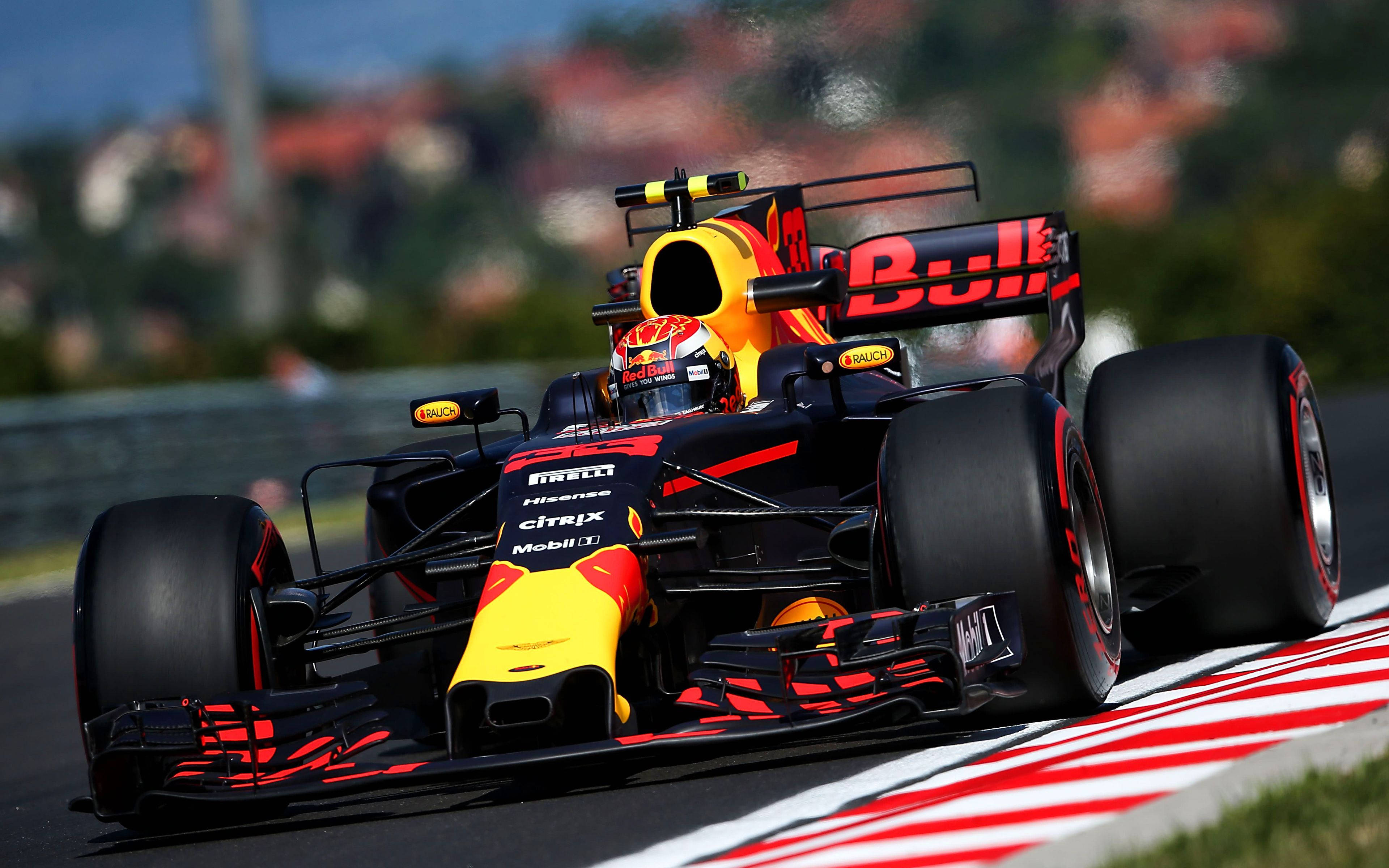 Verstappen 桌布 壁紙 — 一輛紅牛一級方程式賽車在明亮的日光下，在設有紅色和白色路緣的賽道上飛馳。