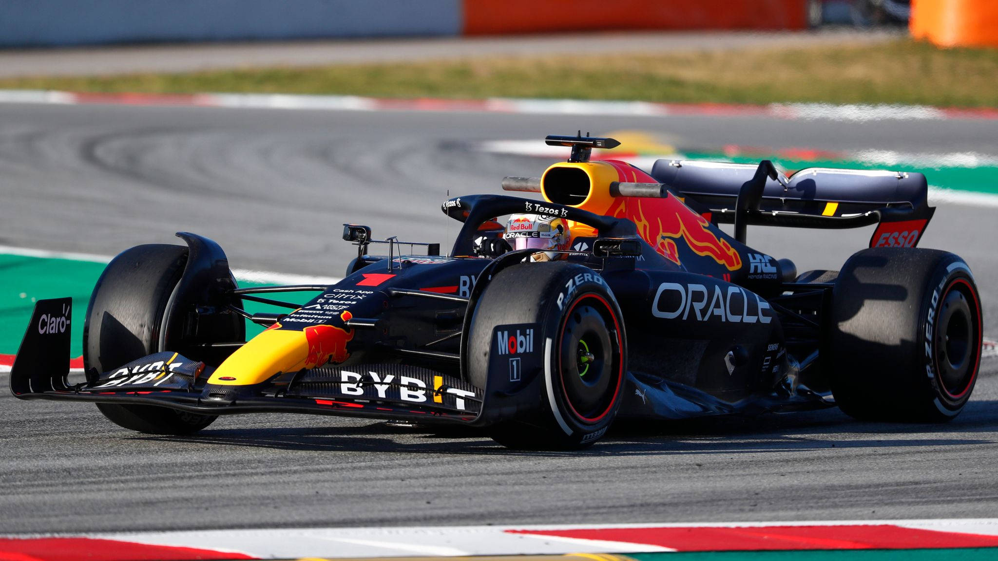 Verstappen 桌布 壁紙 — 一輛紅牛車隊一級方程式賽車在賽道彎位疾馳，帶有鮮明的贊助商標誌和空氣動力學設計。