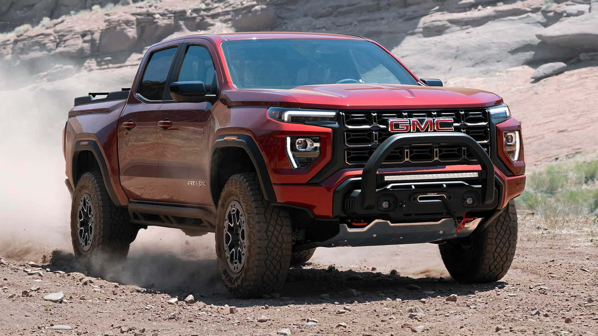 Gmc Canyon 桌布 壁紙 — 一輛紅色GMC Canyon AT4皮卡車在崎嶇的沙漠峽谷中疾馳，揚起灰塵。