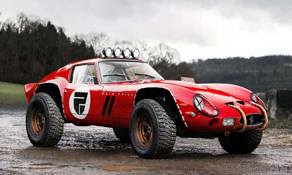 Off-road Car 桌布 壁紙 — 一輛紅色法拉利250 GTO拉力賽車，配備超大輪胎和車頂燈，停放在泥濘地形上，天空多雲。