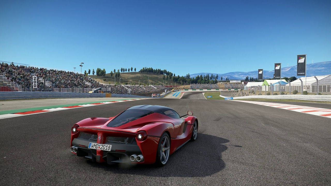 Project Cars 2 LaFerrari 壁紙 — 一輛紅色法拉利LaFerrari在陽光明媚的賽道上奔馳，周圍有歡呼的人群和遠處的山脈，天空清澈湛藍。