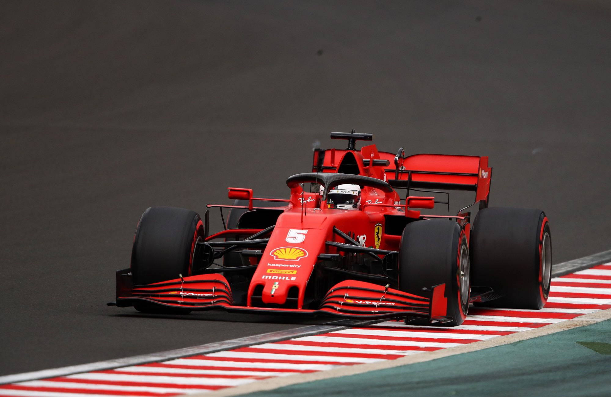 sebastian vettel 桌布 壁紙 — 一輛紅色法拉利一級方程式賽車（5號）在紅白相間的路緣賽道上奔馳。