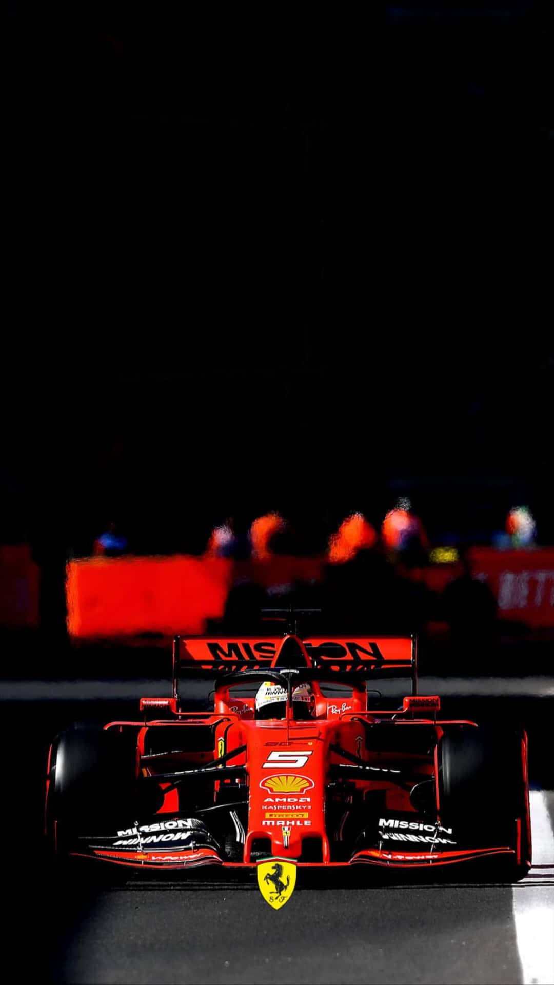 Scuderia Ferrari iPhone X 壁紙 — 一輛紅色法拉利一級方程式賽車在夜間被賽道燈光照亮，背景有模糊的觀眾。