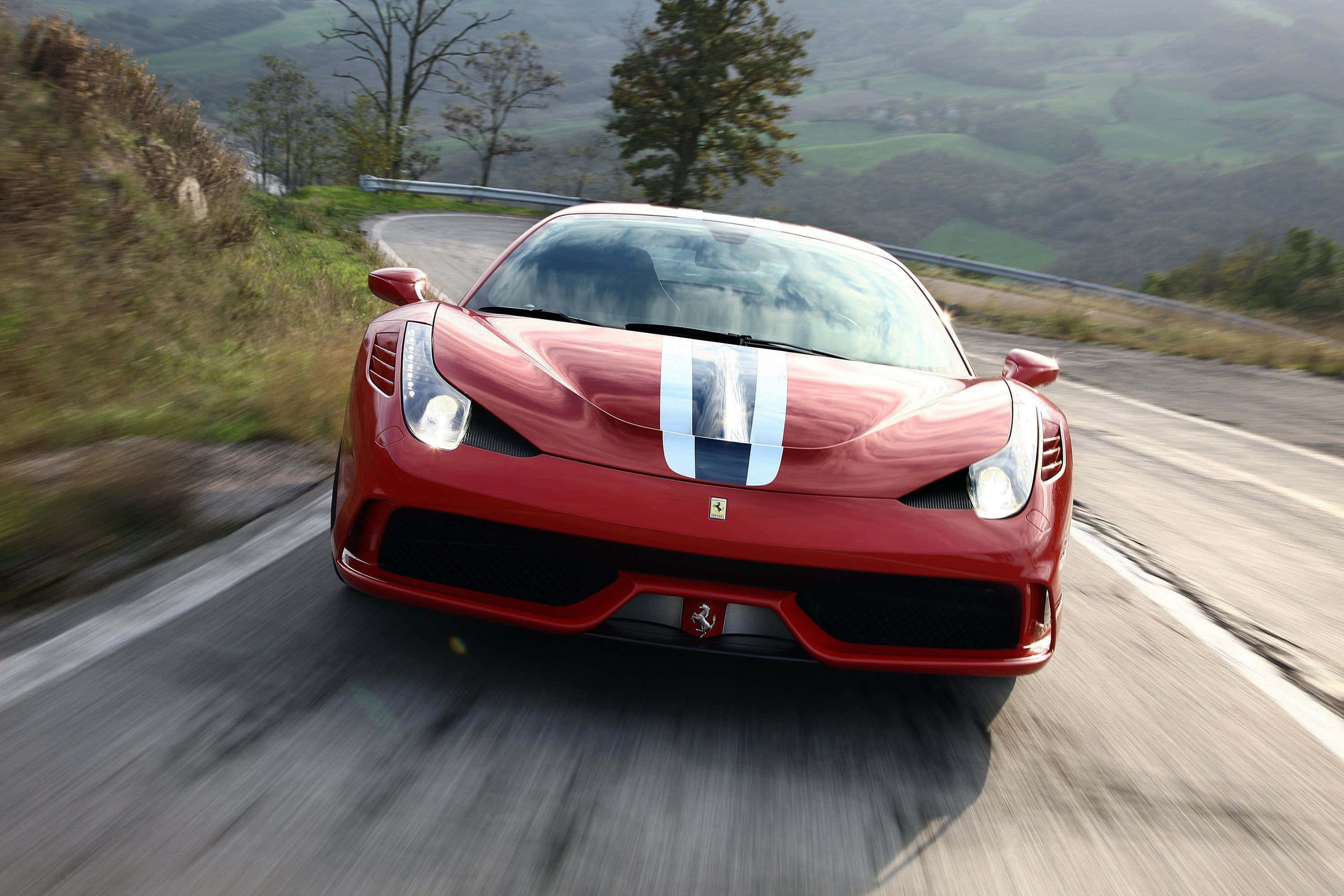 Ferrari 458 Speciale 桌布 壁紙 — 一輛紅色法拉利在蜿蜒的山路上高速行駛，背景有模糊的動感和綠色的山丘。