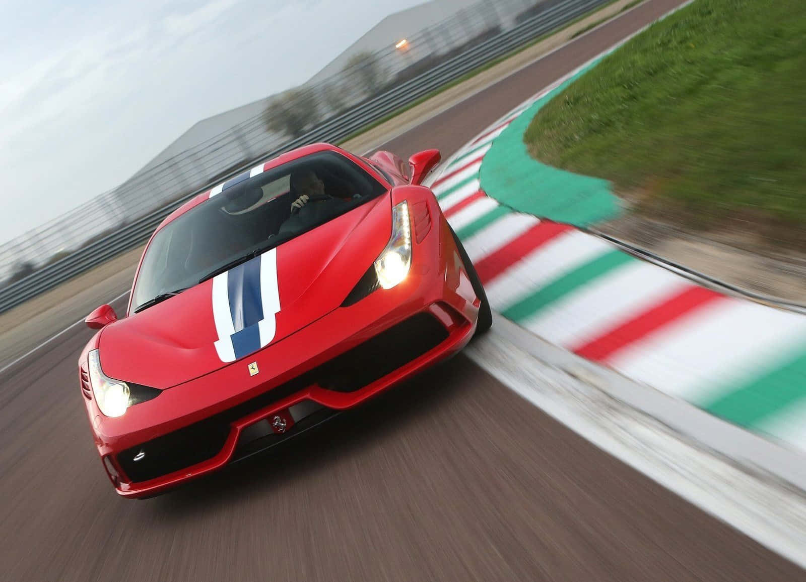 Ferrari 458 Speciale 桌布 壁紙 — 一輛紅色法拉利在賽道彎位高速行駛，帶有動態模糊效果和意大利國旗路緣石。