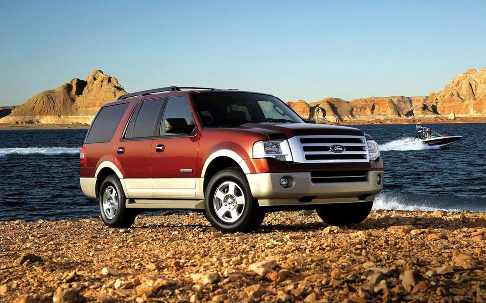 Ford Expedition 桌布 壁紙 — 一輛紅色福特Expedition SUV停泊在岩石湖岸上，身後一艘快艇在清澈藍天下劃破水面。