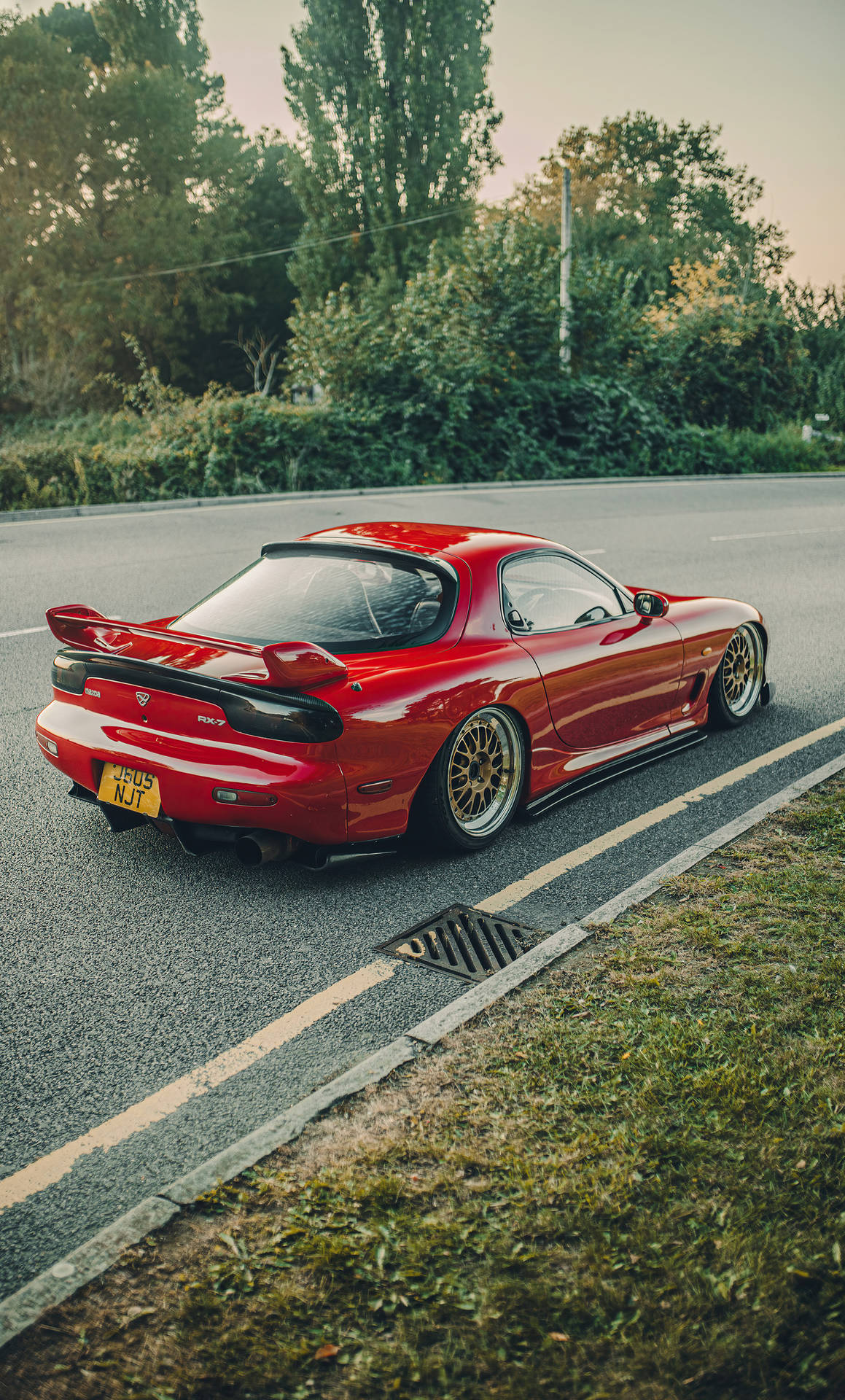 紅色Mazda RX-7跑車在日落時停泊在鄉村道路上。