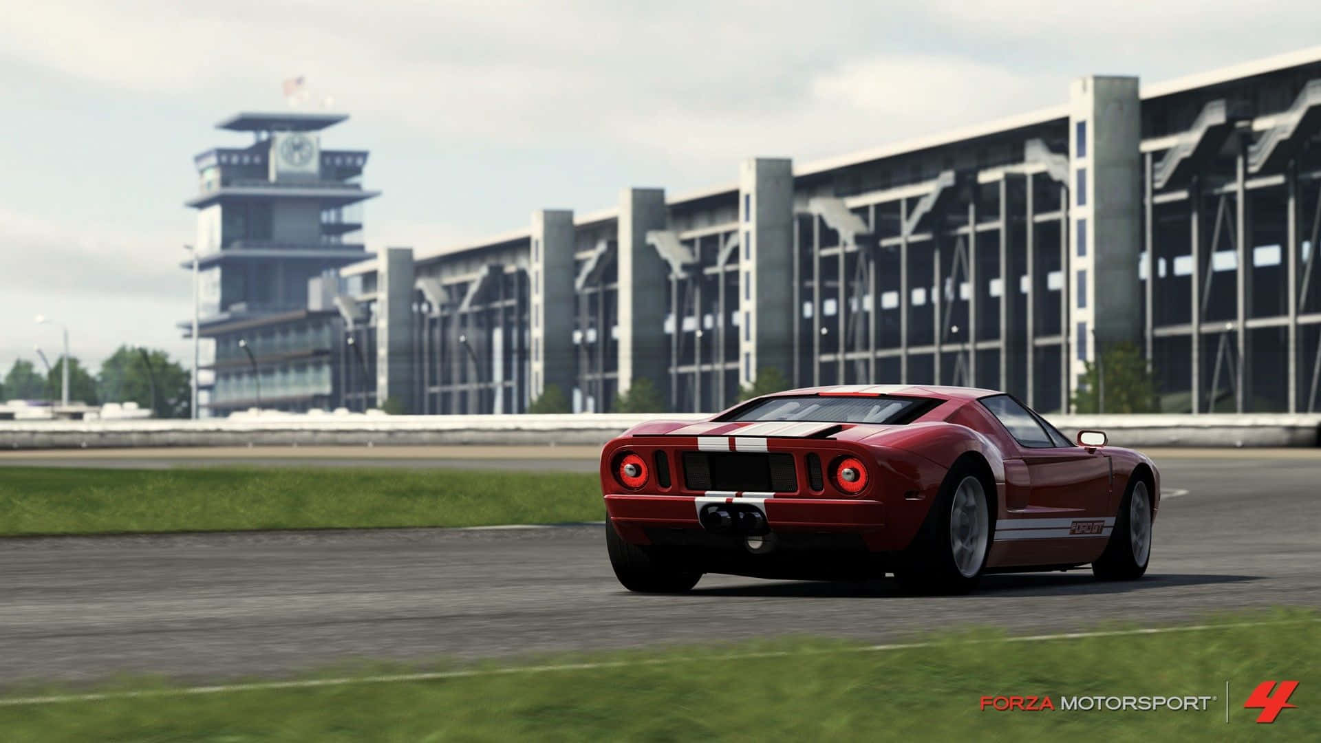 紅色福特GT40賽車在賽道上，有看台和控制塔。