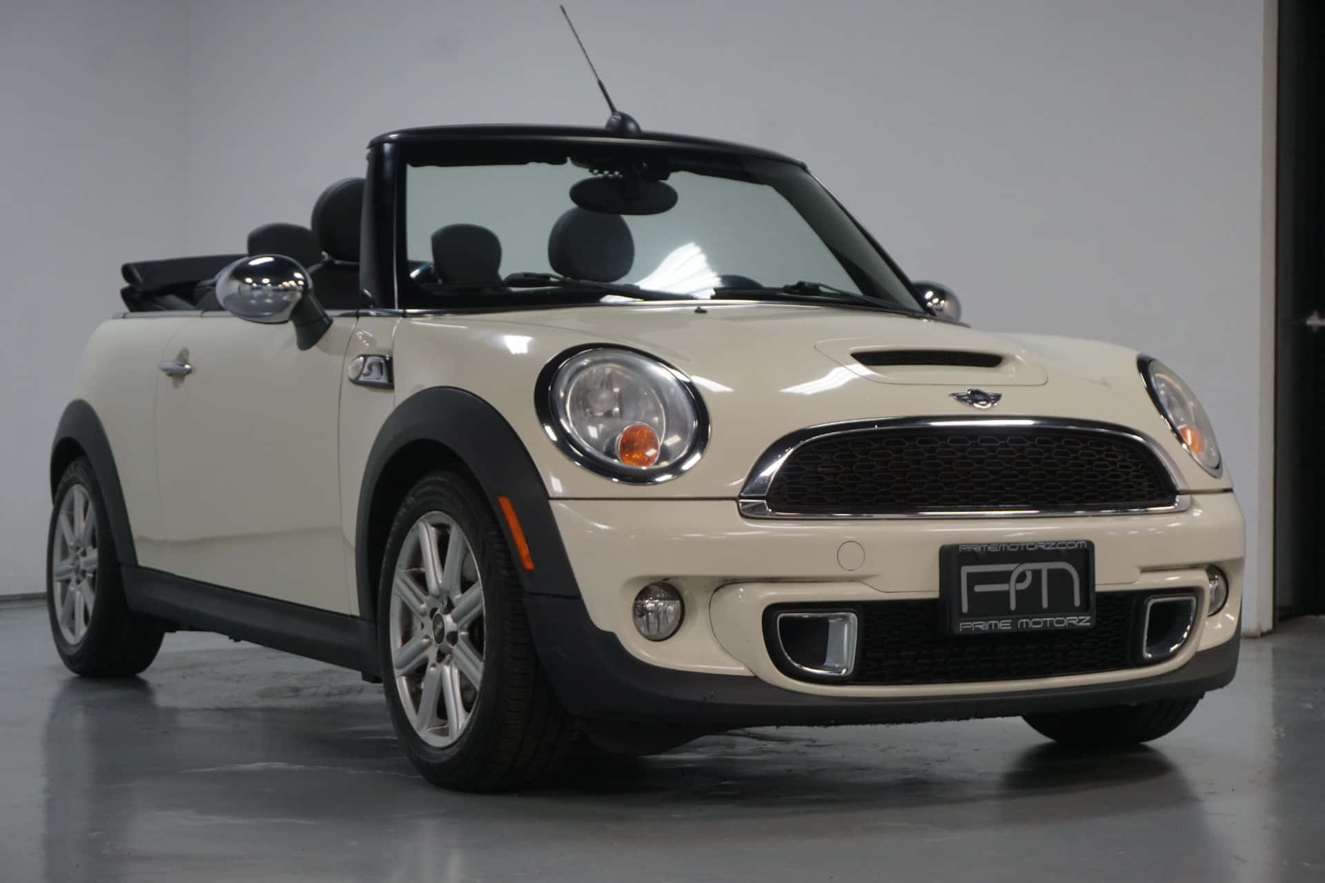 Mini Cooper S Convertible 桌布 壁紙 — 一輛純淨的奶油色Mini Cooper開篷車，帶有黑色飾件和銀色輪圈，在明亮的攝影棚燈光下停放在室內。