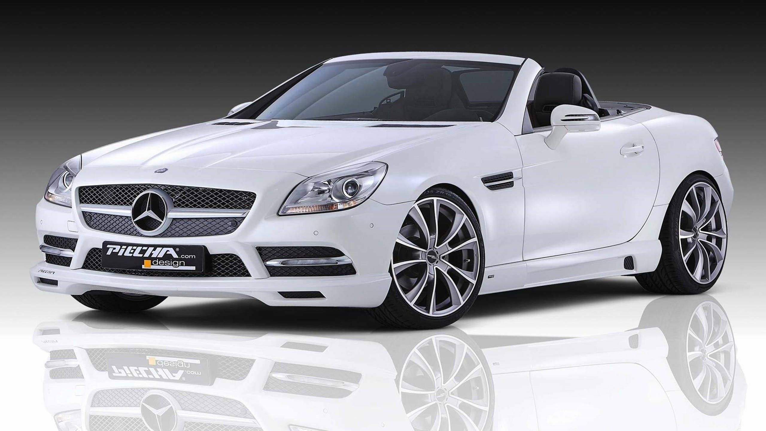 HD 桌布 壁紙 — 一輛純白色的 Mercedes-Benz SLK 開篷跑車，配備定製的 Piecha Design 輪圈，在深色漸變背景的反射工作室地板上展示。