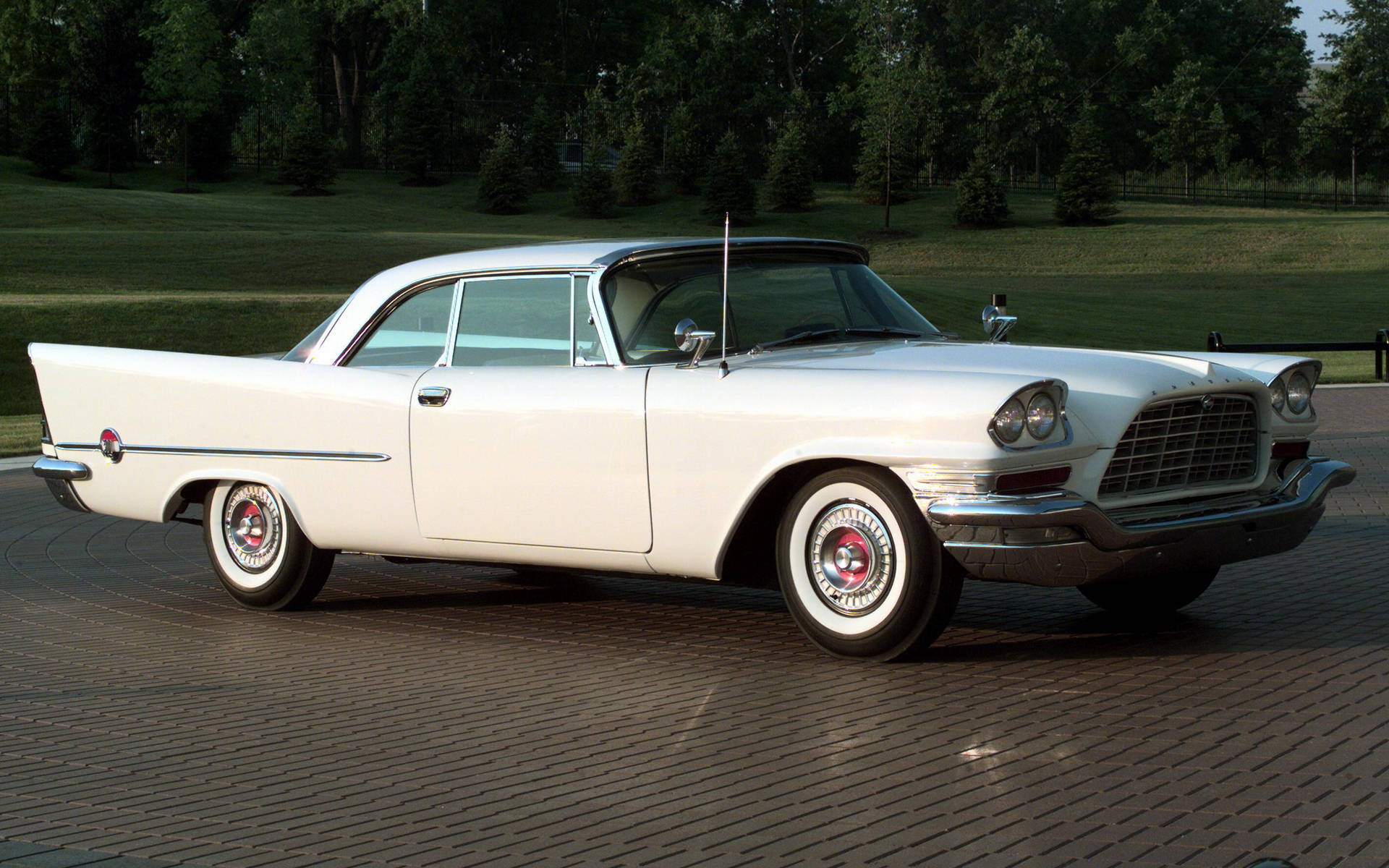 Chrysler 300 Letter 壁紙 — 一輛純白色的1950年代經典汽車在柔和陽光下，於鋪砌的車道上閃閃發光，周圍環繞著茂密的綠樹。