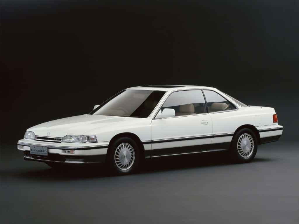 Honda Legend 桌布 壁紙 — 一輛純白色的1980年代本田Legend轎跑車在攝影棚燈光下閃耀，背景為深色漸變。