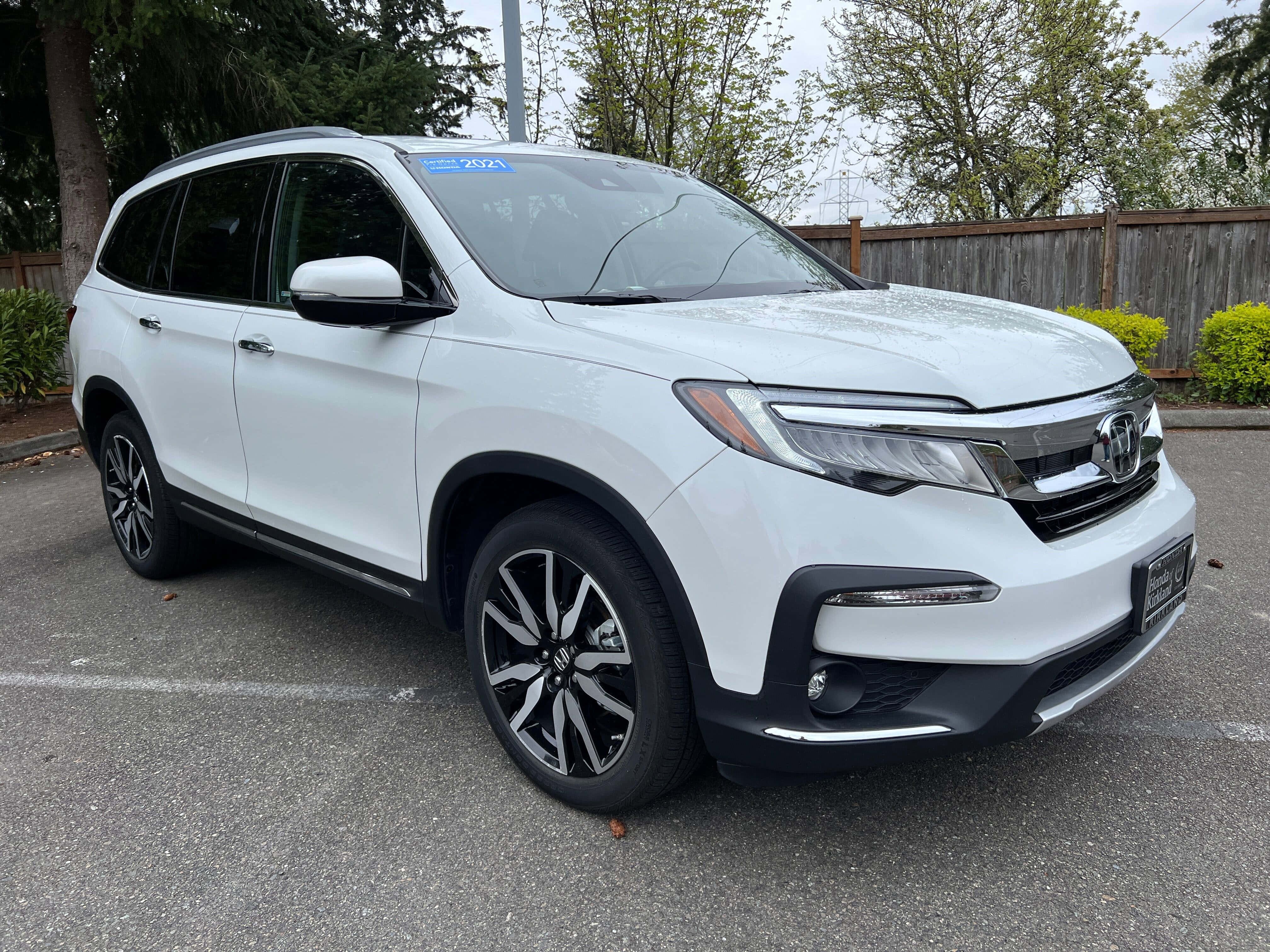 Honda Pilot 桌布 壁紙 — 一輛純白色的2021年本田Pilot SUV停泊在瀝青停車場，背景有樹木和木柵欄。