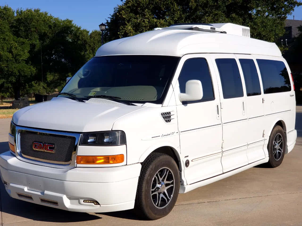 Gmc Savana 桌布 壁紙 — 一輛純白色的GMC房車停在陽光明媚的日子裡，背景是茂密的綠樹。
