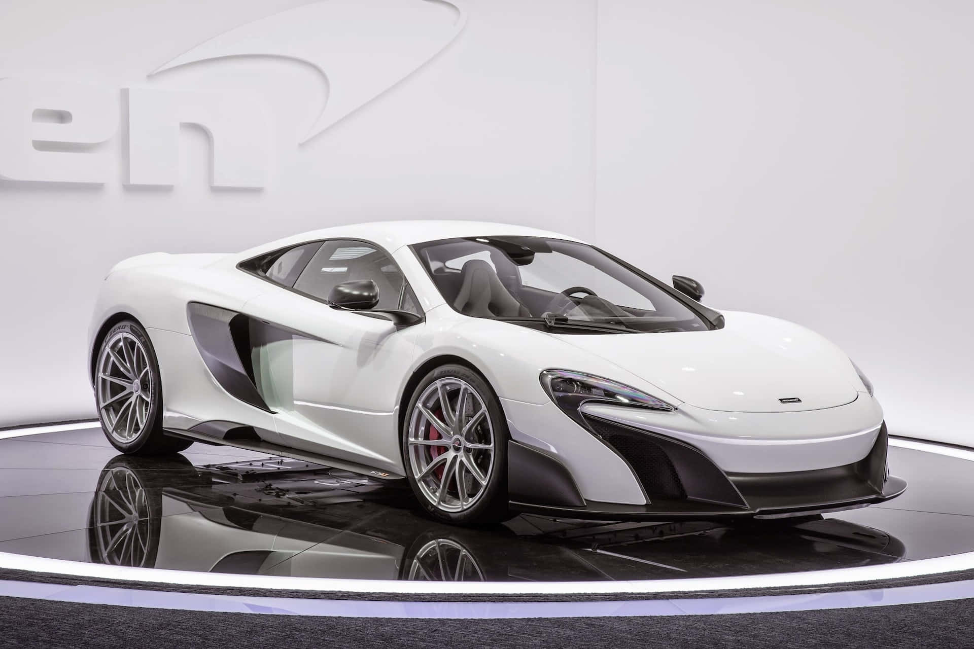 Mclaren 675lt Spider 桌布 壁紙 — 一輛純白色的McLaren跑車在攝影棚燈光下，於反射黑色平台上，以簡約白色背景襯托，閃閃發光。