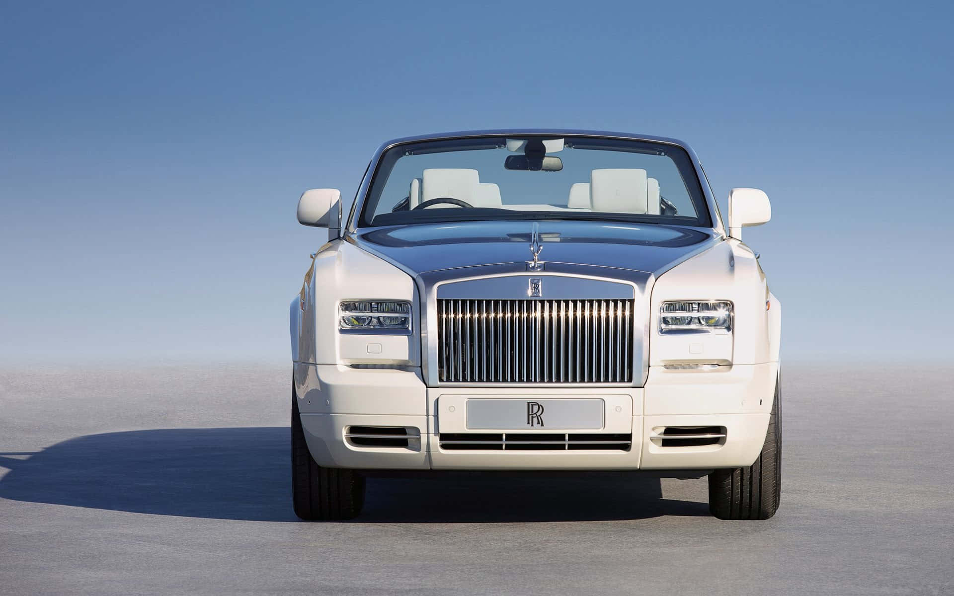 Rolls Royce 桌布 壁紙 — 一輛純白色的勞斯萊斯幻影Drophead Coupe在晴朗的藍天下，矗立於廣闊的沙漠平原上。